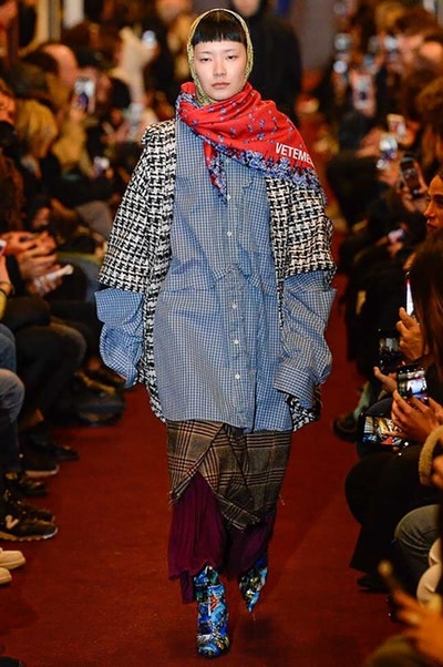 デムナワールドが炸裂した Vetements 2018年秋冬コレクション ストリート＆オーバーサイズという真骨頂の中でスカーフと壊滅的なミリタリーパンツを提案した圧巻のランウェイ パリファッションウィークの公式スケジュールから脱退した〈Vetements（ヴェトモン）〉が、レッドカーペットを敷き詰めた会場で宣言通りの単独ショーを開催した。ストリートとルーズシルエットというDemna Gvasalia（デムナ・ヴァザリア）の真骨頂の中で印象的に映るのは、スカーフの提案と壊滅的に近いミリタリーパンツのダメージ加工。落書きやワッペンの配置、多様多種な柄物のミックスからは、80年代〜90年代のヴィンテージ古着に見るカオティックな雰囲気が漂うほか、Marilyn Manson（マリリン・マンソン）のシャツなども組み込まれ、何とも形容し難いDemnaならではの世界観を構築して観衆を釘付けにした。 ちなみに、下のInstagramの動画はインビテーションであるレシートを撮影したもの。見応え満載の全57体のルックはフォトギャラリーからご確認を。 〈Vetements〉と〈Reebok（リーボック）〉によるブルーを効かせたGenetically Modified Pumpの限定カラーもお買い逃しのないように。