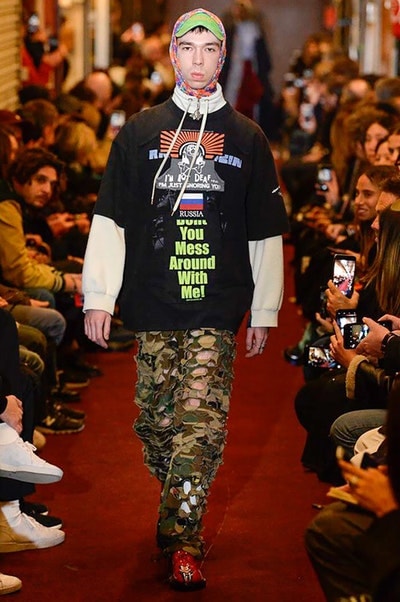 デムナワールドが炸裂した Vetements 2018年秋冬コレクション ストリート＆オーバーサイズという真骨頂の中でスカーフと壊滅的なミリタリーパンツを提案した圧巻のランウェイ パリファッションウィークの公式スケジュールから脱退した〈Vetements（ヴェトモン）〉が、レッドカーペットを敷き詰めた会場で宣言通りの単独ショーを開催した。ストリートとルーズシルエットというDemna Gvasalia（デムナ・ヴァザリア）の真骨頂の中で印象的に映るのは、スカーフの提案と壊滅的に近いミリタリーパンツのダメージ加工。落書きやワッペンの配置、多様多種な柄物のミックスからは、80年代〜90年代のヴィンテージ古着に見るカオティックな雰囲気が漂うほか、Marilyn Manson（マリリン・マンソン）のシャツなども組み込まれ、何とも形容し難いDemnaならではの世界観を構築して観衆を釘付けにした。 ちなみに、下のInstagramの動画はインビテーションであるレシートを撮影したもの。見応え満載の全57体のルックはフォトギャラリーからご確認を。 〈Vetements〉と〈Reebok（リーボック）〉によるブルーを効かせたGenetically Modified Pumpの限定カラーもお買い逃しのないように。