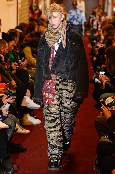デムナワールドが炸裂した Vetements 2018年秋冬コレクション ストリート＆オーバーサイズという真骨頂の中でスカーフと壊滅的なミリタリーパンツを提案した圧巻のランウェイ パリファッションウィークの公式スケジュールから脱退した〈Vetements（ヴェトモン）〉が、レッドカーペットを敷き詰めた会場で宣言通りの単独ショーを開催した。ストリートとルーズシルエットというDemna Gvasalia（デムナ・ヴァザリア）の真骨頂の中で印象的に映るのは、スカーフの提案と壊滅的に近いミリタリーパンツのダメージ加工。落書きやワッペンの配置、多様多種な柄物のミックスからは、80年代〜90年代のヴィンテージ古着に見るカオティックな雰囲気が漂うほか、Marilyn Manson（マリリン・マンソン）のシャツなども組み込まれ、何とも形容し難いDemnaならではの世界観を構築して観衆を釘付けにした。 ちなみに、下のInstagramの動画はインビテーションであるレシートを撮影したもの。見応え満載の全57体のルックはフォトギャラリーからご確認を。 〈Vetements〉と〈Reebok（リーボック）〉によるブルーを効かせたGenetically Modified Pumpの限定カラーもお買い逃しのないように。
