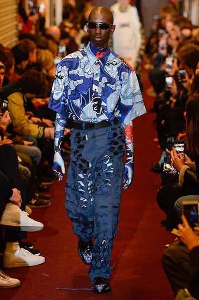 デムナワールドが炸裂した Vetements 2018年秋冬コレクション ストリート＆オーバーサイズという真骨頂の中でスカーフと壊滅的なミリタリーパンツを提案した圧巻のランウェイ パリファッションウィークの公式スケジュールから脱退した〈Vetements（ヴェトモン）〉が、レッドカーペットを敷き詰めた会場で宣言通りの単独ショーを開催した。ストリートとルーズシルエットというDemna Gvasalia（デムナ・ヴァザリア）の真骨頂の中で印象的に映るのは、スカーフの提案と壊滅的に近いミリタリーパンツのダメージ加工。落書きやワッペンの配置、多様多種な柄物のミックスからは、80年代〜90年代のヴィンテージ古着に見るカオティックな雰囲気が漂うほか、Marilyn Manson（マリリン・マンソン）のシャツなども組み込まれ、何とも形容し難いDemnaならではの世界観を構築して観衆を釘付けにした。 ちなみに、下のInstagramの動画はインビテーションであるレシートを撮影したもの。見応え満載の全57体のルックはフォトギャラリーからご確認を。 〈Vetements〉と〈Reebok（リーボック）〉によるブルーを効かせたGenetically Modified Pumpの限定カラーもお買い逃しのないように。