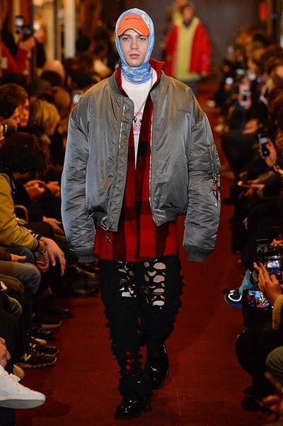 デムナワールドが炸裂した Vetements 2018年秋冬コレクション ストリート＆オーバーサイズという真骨頂の中でスカーフと壊滅的なミリタリーパンツを提案した圧巻のランウェイ パリファッションウィークの公式スケジュールから脱退した〈Vetements（ヴェトモン）〉が、レッドカーペットを敷き詰めた会場で宣言通りの単独ショーを開催した。ストリートとルーズシルエットというDemna Gvasalia（デムナ・ヴァザリア）の真骨頂の中で印象的に映るのは、スカーフの提案と壊滅的に近いミリタリーパンツのダメージ加工。落書きやワッペンの配置、多様多種な柄物のミックスからは、80年代〜90年代のヴィンテージ古着に見るカオティックな雰囲気が漂うほか、Marilyn Manson（マリリン・マンソン）のシャツなども組み込まれ、何とも形容し難いDemnaならではの世界観を構築して観衆を釘付けにした。 ちなみに、下のInstagramの動画はインビテーションであるレシートを撮影したもの。見応え満載の全57体のルックはフォトギャラリーからご確認を。 〈Vetements〉と〈Reebok（リーボック）〉によるブルーを効かせたGenetically Modified Pumpの限定カラーもお買い逃しのないように。