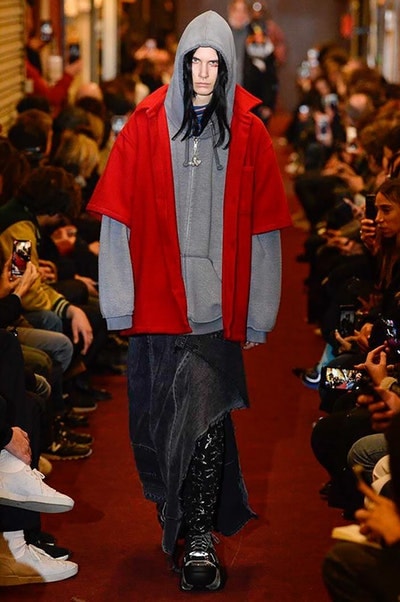 デムナワールドが炸裂した Vetements 2018年秋冬コレクション ストリート＆オーバーサイズという真骨頂の中でスカーフと壊滅的なミリタリーパンツを提案した圧巻のランウェイ パリファッションウィークの公式スケジュールから脱退した〈Vetements（ヴェトモン）〉が、レッドカーペットを敷き詰めた会場で宣言通りの単独ショーを開催した。ストリートとルーズシルエットというDemna Gvasalia（デムナ・ヴァザリア）の真骨頂の中で印象的に映るのは、スカーフの提案と壊滅的に近いミリタリーパンツのダメージ加工。落書きやワッペンの配置、多様多種な柄物のミックスからは、80年代〜90年代のヴィンテージ古着に見るカオティックな雰囲気が漂うほか、Marilyn Manson（マリリン・マンソン）のシャツなども組み込まれ、何とも形容し難いDemnaならではの世界観を構築して観衆を釘付けにした。 ちなみに、下のInstagramの動画はインビテーションであるレシートを撮影したもの。見応え満載の全57体のルックはフォトギャラリーからご確認を。 〈Vetements〉と〈Reebok（リーボック）〉によるブルーを効かせたGenetically Modified Pumpの限定カラーもお買い逃しのないように。
