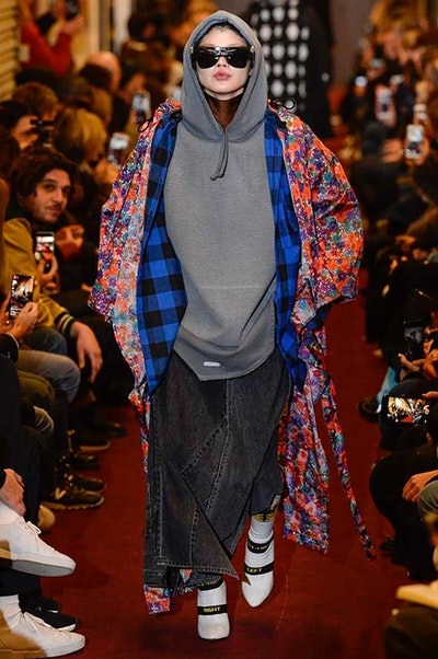 デムナワールドが炸裂した Vetements 2018年秋冬コレクション ストリート＆オーバーサイズという真骨頂の中でスカーフと壊滅的なミリタリーパンツを提案した圧巻のランウェイ パリファッションウィークの公式スケジュールから脱退した〈Vetements（ヴェトモン）〉が、レッドカーペットを敷き詰めた会場で宣言通りの単独ショーを開催した。ストリートとルーズシルエットというDemna Gvasalia（デムナ・ヴァザリア）の真骨頂の中で印象的に映るのは、スカーフの提案と壊滅的に近いミリタリーパンツのダメージ加工。落書きやワッペンの配置、多様多種な柄物のミックスからは、80年代〜90年代のヴィンテージ古着に見るカオティックな雰囲気が漂うほか、Marilyn Manson（マリリン・マンソン）のシャツなども組み込まれ、何とも形容し難いDemnaならではの世界観を構築して観衆を釘付けにした。 ちなみに、下のInstagramの動画はインビテーションであるレシートを撮影したもの。見応え満載の全57体のルックはフォトギャラリーからご確認を。 〈Vetements〉と〈Reebok（リーボック）〉によるブルーを効かせたGenetically Modified Pumpの限定カラーもお買い逃しのないように。