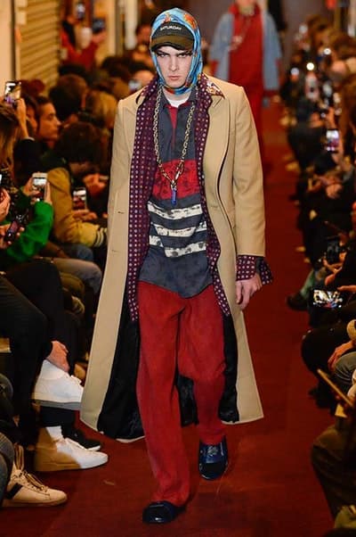 デムナワールドが炸裂した Vetements 2018年秋冬コレクション ストリート&オーバーサイズという真骨頂の中でスカーフと壊滅的なミリタリーパンツを提案した圧巻のランウェイ パリファッションウィークの公式スケジュールから脱退した〈Vetements(ヴェトモン)〉が、レッドカーペットを敷き詰めた会場で宣言通りの単独ショーを開催した。ストリートとルーズシルエットというDemna Gvasalia(デムナ・ヴァザリア)の真骨頂の中で印象的に映るのは、スカーフの提案と壊滅的に近いミリタリーパンツのダメージ加工。落書きやワッペンの配置、多様多種な柄物のミックスからは、80年代〜90年代のヴィンテージ古着に見るカオティックな雰囲気が漂うほか、Marilyn Manson(マリリン・マンソン)のシャツなども組み込まれ、何とも形容し難いDemnaならではの世界観を構築して観衆を釘付けにした。 ちなみに、下のInstagramの動画はインビテーションであるレシートを撮影したもの。見応え満載の全57体のルックはフォトギャラリーからご確認を。 〈Vetements〉と〈Reebok(リーボック)〉によるブルーを効かせたGenetically Modified Pumpの限定カラーもお買い逃しのないように。