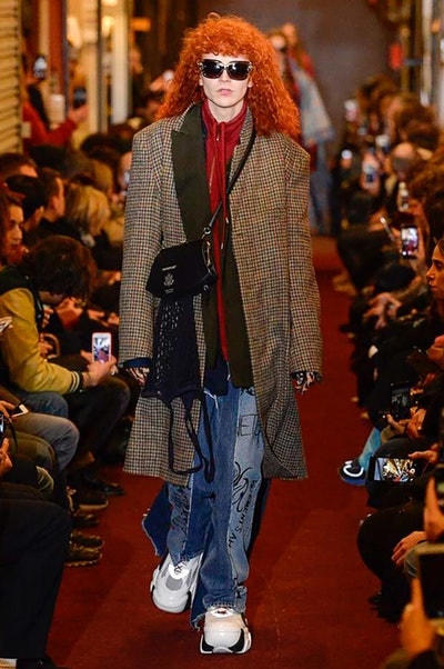 デムナワールドが炸裂した Vetements 2018年秋冬コレクション ストリート＆オーバーサイズという真骨頂の中でスカーフと壊滅的なミリタリーパンツを提案した圧巻のランウェイ パリファッションウィークの公式スケジュールから脱退した〈Vetements（ヴェトモン）〉が、レッドカーペットを敷き詰めた会場で宣言通りの単独ショーを開催した。ストリートとルーズシルエットというDemna Gvasalia（デムナ・ヴァザリア）の真骨頂の中で印象的に映るのは、スカーフの提案と壊滅的に近いミリタリーパンツのダメージ加工。落書きやワッペンの配置、多様多種な柄物のミックスからは、80年代〜90年代のヴィンテージ古着に見るカオティックな雰囲気が漂うほか、Marilyn Manson（マリリン・マンソン）のシャツなども組み込まれ、何とも形容し難いDemnaならではの世界観を構築して観衆を釘付けにした。 ちなみに、下のInstagramの動画はインビテーションであるレシートを撮影したもの。見応え満載の全57体のルックはフォトギャラリーからご確認を。 〈Vetements〉と〈Reebok（リーボック）〉によるブルーを効かせたGenetically Modified Pumpの限定カラーもお買い逃しのないように。
