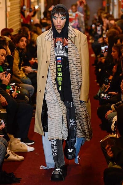 デムナワールドが炸裂した Vetements 2018年秋冬コレクション ストリート&オーバーサイズという真骨頂の中でスカーフと壊滅的なミリタリーパンツを提案した圧巻のランウェイ パリファッションウィークの公式スケジュールから脱退した〈Vetements(ヴェトモン)〉が、レッドカーペットを敷き詰めた会場で宣言通りの単独ショーを開催した。ストリートとルーズシルエットというDemna Gvasalia(デムナ・ヴァザリア)の真骨頂の中で印象的に映るのは、スカーフの提案と壊滅的に近いミリタリーパンツのダメージ加工。落書きやワッペンの配置、多様多種な柄物のミックスからは、80年代〜90年代のヴィンテージ古着に見るカオティックな雰囲気が漂うほか、Marilyn Manson(マリリン・マンソン)のシャツなども組み込まれ、何とも形容し難いDemnaならではの世界観を構築して観衆を釘付けにした。 ちなみに、下のInstagramの動画はインビテーションであるレシートを撮影したもの。見応え満載の全57体のルックはフォトギャラリーからご確認を。 〈Vetements〉と〈Reebok(リーボック)〉によるブルーを効かせたGenetically Modified Pumpの限定カラーもお買い逃しのないように。