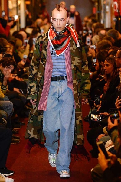 デムナワールドが炸裂した Vetements 2018年秋冬コレクション ストリート＆オーバーサイズという真骨頂の中でスカーフと壊滅的なミリタリーパンツを提案した圧巻のランウェイ パリファッションウィークの公式スケジュールから脱退した〈Vetements（ヴェトモン）〉が、レッドカーペットを敷き詰めた会場で宣言通りの単独ショーを開催した。ストリートとルーズシルエットというDemna Gvasalia（デムナ・ヴァザリア）の真骨頂の中で印象的に映るのは、スカーフの提案と壊滅的に近いミリタリーパンツのダメージ加工。落書きやワッペンの配置、多様多種な柄物のミックスからは、80年代〜90年代のヴィンテージ古着に見るカオティックな雰囲気が漂うほか、Marilyn Manson（マリリン・マンソン）のシャツなども組み込まれ、何とも形容し難いDemnaならではの世界観を構築して観衆を釘付けにした。 ちなみに、下のInstagramの動画はインビテーションであるレシートを撮影したもの。見応え満載の全57体のルックはフォトギャラリーからご確認を。 〈Vetements〉と〈Reebok（リーボック）〉によるブルーを効かせたGenetically Modified Pumpの限定カラーもお買い逃しのないように。