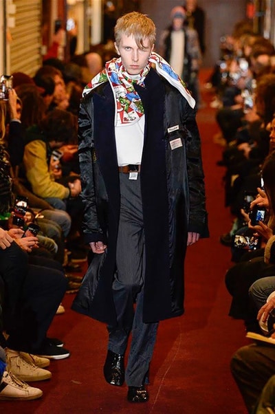 デムナワールドが炸裂した Vetements 2018年秋冬コレクション ストリート＆オーバーサイズという真骨頂の中でスカーフと壊滅的なミリタリーパンツを提案した圧巻のランウェイ パリファッションウィークの公式スケジュールから脱退した〈Vetements（ヴェトモン）〉が、レッドカーペットを敷き詰めた会場で宣言通りの単独ショーを開催した。ストリートとルーズシルエットというDemna Gvasalia（デムナ・ヴァザリア）の真骨頂の中で印象的に映るのは、スカーフの提案と壊滅的に近いミリタリーパンツのダメージ加工。落書きやワッペンの配置、多様多種な柄物のミックスからは、80年代〜90年代のヴィンテージ古着に見るカオティックな雰囲気が漂うほか、Marilyn Manson（マリリン・マンソン）のシャツなども組み込まれ、何とも形容し難いDemnaならではの世界観を構築して観衆を釘付けにした。 ちなみに、下のInstagramの動画はインビテーションであるレシートを撮影したもの。見応え満載の全57体のルックはフォトギャラリーからご確認を。 〈Vetements〉と〈Reebok（リーボック）〉によるブルーを効かせたGenetically Modified Pumpの限定カラーもお買い逃しのないように。