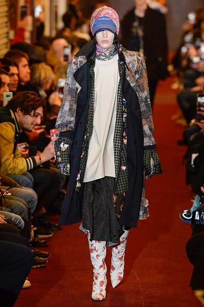 デムナワールドが炸裂した Vetements 2018年秋冬コレクション ストリート＆オーバーサイズという真骨頂の中でスカーフと壊滅的なミリタリーパンツを提案した圧巻のランウェイ パリファッションウィークの公式スケジュールから脱退した〈Vetements（ヴェトモン）〉が、レッドカーペットを敷き詰めた会場で宣言通りの単独ショーを開催した。ストリートとルーズシルエットというDemna Gvasalia（デムナ・ヴァザリア）の真骨頂の中で印象的に映るのは、スカーフの提案と壊滅的に近いミリタリーパンツのダメージ加工。落書きやワッペンの配置、多様多種な柄物のミックスからは、80年代〜90年代のヴィンテージ古着に見るカオティックな雰囲気が漂うほか、Marilyn Manson（マリリン・マンソン）のシャツなども組み込まれ、何とも形容し難いDemnaならではの世界観を構築して観衆を釘付けにした。 ちなみに、下のInstagramの動画はインビテーションであるレシートを撮影したもの。見応え満載の全57体のルックはフォトギャラリーからご確認を。 〈Vetements〉と〈Reebok（リーボック）〉によるブルーを効かせたGenetically Modified Pumpの限定カラーもお買い逃しのないように。