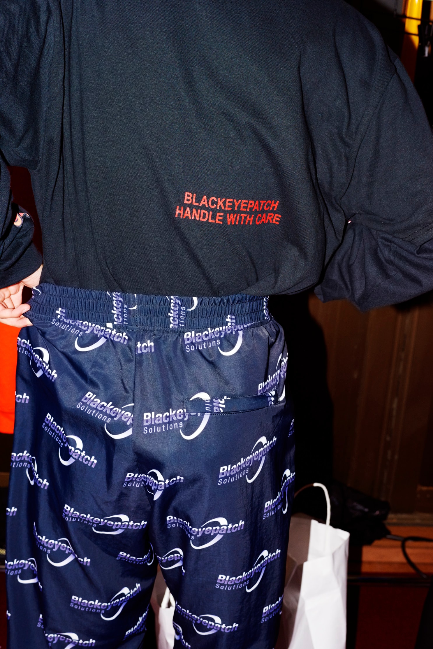 BlackEyePatch が2000年初頭から中期のNYヒップホップシーンをヒントにした2018年春夏コレクションのルックブックを公開 ルックブックの舞台は2018年春夏の“AT TOKYO”で開催したランウェイのバックステージ ルックブックの舞台は2018年春夏の“AT TOKYO”で開催したランウェイのバックステージ “東京”をアイデンティティに、様々なカルチャー的背景を持ちながら、神出鬼没に活動する〈BlackEyePatch（ブラックアイパッチ）〉より、2018年春夏コレクションのルックブックが到着した。舞台は「Amazon Fashion Week TOKYO 2018 Spring/Summer」の特別プログラム、“AT TOKYO”に参加した際のバックステージ。今季はグラフィティライターに欠かせない業務用ステッカーから、“取扱注意”のモチーフが目に止まるが、その他にも〈BEP〉のルーツのひとつでもある00年～05年辺りのニューヨーク・ヒップホップにも傾倒している。  その例としては、’03年頃に流行したラグジュアリーカーの代名詞「Rolls Royce（ロールス・ロイス）」へのオマージュがひとつ。また、モバイル企業広告のアーティスト起用とラッパーたちのミュージックビデオに度々モバイルフォンが登場したという相互関係を汲み取り、テック系の企業ロゴをイメージした“BlackEyePatch SOLUTIONS”などが挙げられる。加えて、〈Ed Hardy（エド ハーディー）〉、〈Von Dutch（ボン ダッチ）〉、〈True Religion（トゥルー レリジョン）〉といった’00年中頃のLAセレブスタイルにもヒントを受け、タトゥーのデザインやラインストーンをモチーフにしたアイテムも展開されている。  赤木雄一がシャッターを切った〈BlackEyePatch〉の最新ルックブックは、上のフォトギャラリーからご確認を。あわせて『HYPEBEAST』が独自で撮影した本バックステージの様子も振り返り、コレクションに対する理解を深めてみてはいかがだろうか。
