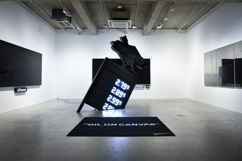 ヴァージル・アブロー初の個展 “PAY PER VIEW” に潜入 メディアや広告に踊らされ、消費によって形作られる現代社会へ向けた異才からのメッセージを体感せよ 良くも悪くもメディアや広告に踊らされ、消費によって形作られる現代社会へ向けた異才からのメッセージ 3月16日(金)より、『Kaikai Kiki Gallery』ではVirgil Abloh(ヴァージル・アブロー)の個展“PAY PER VIEW”が開催されている。「俺たちは全員、消費という行為によって形作られている」、そんなキャッチコピーを掲げる本展では、メディアが人類による世界の見方にいかに重大な影響を与えているのかを示すものだ。 ひとつめの部屋の中央には、モーターレース「NASCAR(ナスカー)」の公式スポンサーである石油会社「SUNOCO(スノコ)」の脚の折れたガソリンスタンド看板が鎮座。また、そのアートピースを背にした正面には、「“ADVERTISE HERE”」の文字が書かれたキャンバスが設置されているが、その下に添えられている電話番号「+1-855-633-9483」はVirgil本人のTwitterにも記載があり、実際にここに電話をかけると〈Off-White™️(オフホワイト)〉のデザイナーが2016年春のコレクション“Blue Collar”の説明をしてくれるのだ。また、ローラーなどは一切使用せず、黒い油絵具と画筆で塗り潰された3,000cm x 1,000cmのキャンバスは、戦前に抽象絵画を手掛けた最初の人物、Kasimir Malevich(カジミール・マレーヴィチ)の作品「黒の正方形」にインスパイアされている。美術史に大きな足跡を残し、存在論や認識論など様々な角度から分析されたこの名画は、視覚的刺激や意味をなすものを排除した完全なる抽象画であるが、Virgilが一人で描き上げたキャンバスの下には、「JCDecaux(ジーセードコー)」、「OUTFRONT(アウトフロント)」、「LAMAR(ラマー)」といった広告企業のロゴが配置。VirgilはMalevichの対話のルールを使って線と線をつなぎ、鑑賞者は広告が持つ力を突き詰めて蒸留したところに残る核心である、という内在的な意図を解き明かしているのだ。 一方、奥の部屋は床一面が畳に。中央に置かれたサイネージに流れてるのは、バルセロナで撮影した〈Off-White™️〉のコレクションムービーだが、「Coca-Cola(コカ・コーラ)」、「DASANI(ダサニ)」、「Perrier(ペリエ)」など、世界的知名度を持つ飲料のロゴを表示するアナログな作品と、スプレーペイントを施した4枚綴りのキャンバスが同居することにより、言葉にしがたい不思議な感覚に陥る空間のミスマッチが生じている。 “PAY PER VIEW”の展示の様子は上のフォトギャラリーよりご確認いただけるが、作品を俯瞰で捉え、感覚を研ぎ澄ますことで伝わってくるVirgilのメッセージはこの空間でしか感じることができない。以下の会期とご自身のスケジュールを照らし合わせ、是非『Kaikai Kiki Gallery』まで足を運んでみてはいかがだろうか。 Virgil Abloh “PAY PER VIEW” @ Kaikai Kiki Gallery 住所:東京都港区元麻布2-3-30 元麻布クレストビルB1 会期:2018年3月16日(金)〜4月1日(日) 時間:11:00 – 19:00 休館日:日、月、祝(最終日の4月1日のみ日曜営業)