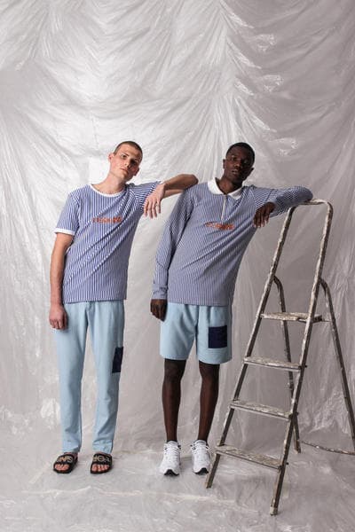 ガーナ発の L’ORIGINE よりシンプルな中にも強いメッセージ性を持った2018年夏コレクションが到着 肌の色の違うモデルや補色を使ったアイテムで人種や民族による隔たりのないオープンな社会を表現 2014年に設立されたガーナ発の新鋭ブランド〈L’ORIGINE（ロリジンヌ）〉が2017年秋冬コレクションに続き、クリーンさが際立つトップスやボトムスから小物類までを網羅した2018年サマーコレクションを発表。  二人のデザイナー、Dyllan Ahinful（ディラン・アヒンフル）とJeffrey Mensah（ジェフリー・メンサー）が率いる同ブランドであるが、今季は“Opposites Attract And Enhance”をテーマとして相違点にフォーカス。肌の色の違う二人のモデルを起用し、補色（互いの色を最も目立たせる色の組み合わせ）を強調することで、性質の異なるものが一緒になり生まれる相乗効果を表わしている。また、カラースキームにおいては、Claude Monet（クロード・モネ）らに代表される印象派にインスパイアされており、パステルブルーとイエローを基調としたアイテムが全ルックに登場、ミニマルな装飾が施されたポロシャツからショーツ、トラックスーツまでが並ぶ。その他にはストライプ柄のシャツや、ベーシックなブラックとホワイトをベースにブランドロゴなどのグラフィックがプリントされたフーディーやナイロン素材のアノラック、ボディバッグやサンダルがラインアップ。  今サマーコレクションは、〈L’ORIGINE〉の公式サイトにて一部のアイテムのプレオーダーを開始している。まずは上のフォトロールより、デザイナーのメッセージが詰まった各ルックをチェックしてみよう。