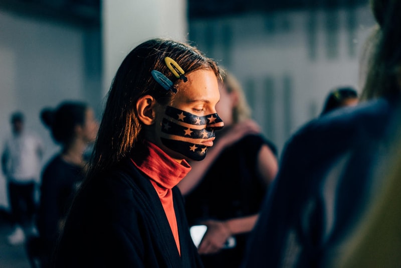 アメリカへの愛を表現した Alexander Wang の最新コレクションの舞台裏に潜入 『MTV』が一斉を風靡した2000年初頭を着想源に、ファッションの震源地であるアメリカが長い歴史で築き上げてきたスタイルの全てを凝縮 シンプルに“COLLECTION 1”というタイトルを掲げ、マンハッタンのハーバーサイド『Pier 19』で開催された〈Alexander Wang（アレキサンダー・ワン）〉の最新ランウェイは、Wangが想うアメリカンドリームと移民としてのルーツを表現したものだった。記録的大ヒットを記録したChildish Gambino（チャイルディッシュ・ガンビーノ）の“This is America”をクロージングソングに採用したショーは、Wangの「移民としてのルーツを持つアメリカ人のプライド」が来場に直に伝わったことだろう。だが、このコレクション自体は、何一つ混じり気のないアメリカ人らしさを称賛するものだったのである。  巨大な正方形の空間にそれと相反するヘヴィメタルのサウンドトラックが響きわたった今回のランウェイは、1980〜90年代の『MTV』や『Times Square』に訪れた観光客の服装など、現代アメリカファッションの原型を色濃く反映している。コレクションの根幹をなすクロップドパンツ、ローライダージーンズ、ケミカルなビブス、頭に巻かれたバンダナは、2000年の「MTV Video Music Awards」に登場したJennifer Lopez（ジェニファー・ロペス）がインスピレーションソース。また、〈adidas（アディダス）〉とのコラボレーションシューズはCrazy 97 EQT Elevationをベースのシルエットに採用しているほか、サングランスと米国への愛国心を感じさせるフェイスペイントも“COLLECTION 1”を象徴するものだった。その他にもオーバーサイズのジャージ、シルエットを誇張したレザージャケット、多様多種なレザーベルト、オンブレシャツ＆ショーツ、ペイズリープリントのボタンアップなど、コレクション全体をレッド/ブラックで統一した〈AW〉の最新コレクションは、ファッションの震源地としてアメリカが築き上げてきたものを凝縮していると言っても過言ではないだろう。  『HYPEBEAST』はそんな“COLLECTION 1”のバックステージに潜入することに成功。是非、ランウェイルックでは確認できないアパレルのディテールなどを上のフォトギャラリーからチェックしてみてほしい。  あわせて、先日デリバリーが完了した〈adidas Originals by Alexander Wang（アディダス オリジナルス バイ アレキサンダー ワン）〉の最新アイテム一覧もお見逃しなく。 HYPEBEAST
