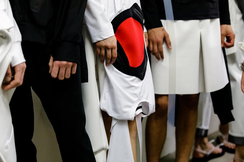 丸龍文人の帰還は、2019年春夏シーズン最大のトピックのひとつだった。〈COMME des GARÇONS（コム デ ギャルソン）〉退社から約2年の時を経て、同氏は自身の名を冠した〈FUMITO GANRYU（フミト ガンリュー）〉を「Pitti Uomo（ピッティ ウォモ）」の“Designer Project”で発表。幸運にも、『HYPEBEAST』はこの新たな船出となるランウェイの舞台裏に潜入する機会を得ることができた。  1stコレクションに言及する前に、〈GANRYU〉の時代を振り返ってみたい。シャツ、デニム、テーラードジャケットなど、ベースとなるカジュアルウェアは決して新鮮味を感じるものではない。だが、丸龍氏の手にかかれば、それらの洋服はモードに寄っていくのではなく、文字通り“昇華”されてしまうのだ。かつて『Union（ユニオン）』のChris Gibbs（クリス・ギブス）も「COMME des GARÇONSファミリーの中で最も完璧なブランドだ。なぜなら、GANRYUはストリートウェア、ワークウェア、ハイファッションを融合しているからである」と『BoF』の中で同氏のクリエイションを手放しに賞賛。それだけ、〈GANRYU〉はどこよりも早く、ランウェイからストリートにリーチしていたのだ。  〈FUMITO GANRYU〉のデビューコレクションは、会場に水の逆光写真が飾られた空間でお披露目を迎えた。ランウェイでは極限までクリーンに仕立てられたスポーツウェアが随所で登場し、カトリックの衣装を彷彿とさせるオーバーサイズのフーディや半透明のクリアベルトを採用したサンダルがキーピースに。そのシルエット美には誰しもが「シーンに丸龍文人が帰ってきた」と感じたことだろう。  〈FUMITO GANRYU〉初のコレクションの細部に迫るバックステージフォトは、上のフォトギャラリーから。取扱店舗などの詳細は、@fumitoganryuなどを含め、ブランドからのアップデートを待とう。  あわせて、先日閉幕したロンドンファッションウィーク・メンズ期間中に敢行したストリートスナップもお見逃しなく。
