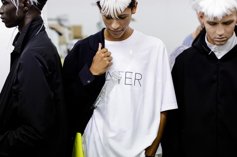丸龍文人の帰還は、2019年春夏シーズン最大のトピックのひとつだった。〈COMME des GARÇONS（コム デ ギャルソン）〉退社から約2年の時を経て、同氏は自身の名を冠した〈FUMITO GANRYU（フミト ガンリュー）〉を「Pitti Uomo（ピッティ ウォモ）」の“Designer Project”で発表。幸運にも、『HYPEBEAST』はこの新たな船出となるランウェイの舞台裏に潜入する機会を得ることができた。  1stコレクションに言及する前に、〈GANRYU〉の時代を振り返ってみたい。シャツ、デニム、テーラードジャケットなど、ベースとなるカジュアルウェアは決して新鮮味を感じるものではない。だが、丸龍氏の手にかかれば、それらの洋服はモードに寄っていくのではなく、文字通り“昇華”されてしまうのだ。かつて『Union（ユニオン）』のChris Gibbs（クリス・ギブス）も「COMME des GARÇONSファミリーの中で最も完璧なブランドだ。なぜなら、GANRYUはストリートウェア、ワークウェア、ハイファッションを融合しているからである」と『BoF』の中で同氏のクリエイションを手放しに賞賛。それだけ、〈GANRYU〉はどこよりも早く、ランウェイからストリートにリーチしていたのだ。  〈FUMITO GANRYU〉のデビューコレクションは、会場に水の逆光写真が飾られた空間でお披露目を迎えた。ランウェイでは極限までクリーンに仕立てられたスポーツウェアが随所で登場し、カトリックの衣装を彷彿とさせるオーバーサイズのフーディや半透明のクリアベルトを採用したサンダルがキーピースに。そのシルエット美には誰しもが「シーンに丸龍文人が帰ってきた」と感じたことだろう。  〈FUMITO GANRYU〉初のコレクションの細部に迫るバックステージフォトは、上のフォトギャラリーから。取扱店舗などの詳細は、@fumitoganryuなどを含め、ブランドからのアップデートを待とう。  あわせて、先日閉幕したロンドンファッションウィーク・メンズ期間中に敢行したストリートスナップもお見逃しなく。