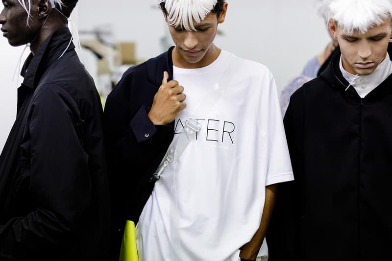 丸龍文人の帰還は、2019年春夏シーズン最大のトピックのひとつだった。〈COMME des GARÇONS(コム デ ギャルソン)〉退社から約2年の時を経て、同氏は自身の名を冠した〈FUMITO GANRYU(フミト ガンリュー)〉を「Pitti Uomo(ピッティ ウォモ)」の“Designer Project”で発表。幸運にも、『HYPEBEAST』はこの新たな船出となるランウェイの舞台裏に潜入する機会を得ることができた。 1stコレクションに言及する前に、〈GANRYU〉の時代を振り返ってみたい。シャツ、デニム、テーラードジャケットなど、ベースとなるカジュアルウェアは決して新鮮味を感じるものではない。だが、丸龍氏の手にかかれば、それらの洋服はモードに寄っていくのではなく、文字通り“昇華”されてしまうのだ。かつて『Union(ユニオン)』のChris Gibbs(クリス・ギブス)も「COMME des GARÇONSファミリーの中で最も完璧なブランドだ。なぜなら、GANRYUはストリートウェア、ワークウェア、ハイファッションを融合しているからである」と『BoF』の中で同氏のクリエイションを手放しに賞賛。それだけ、〈GANRYU〉はどこよりも早く、ランウェイからストリートにリーチしていたのだ。 〈FUMITO GANRYU〉のデビューコレクションは、会場に水の逆光写真が飾られた空間でお披露目を迎えた。ランウェイでは極限までクリーンに仕立てられたスポーツウェアが随所で登場し、カトリックの衣装を彷彿とさせるオーバーサイズのフーディや半透明のクリアベルトを採用したサンダルがキーピースに。そのシルエット美には誰しもが「シーンに丸龍文人が帰ってきた」と感じたことだろう。 〈FUMITO GANRYU〉初のコレクションの細部に迫るバックステージフォトは、上のフォトギャラリーから。取扱店舗などの詳細は、@fumitoganryuなどを含め、ブランドからのアップデートを待とう。 あわせて、先日閉幕したロンドンファッションウィーク・メンズ期間中に敢行したストリートスナップもお見逃しなく。
