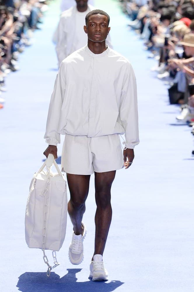 ヴァージル・アブローが手がけた Louis Vuitton 2019年春夏コレクションが遂にお披露目 ファッション界に後世まで語り継がれる歴史的1ページが追加される 〈Louis Vuitton(ルイ ヴィトン)〉がVirgil Abloh(ヴァージル・アブロー)のアーティスティック・ディレクター就任を発表してから早3ヶ月、遂に今をときめくデザイナーの〈LV〉デビューとなる2019年春夏コレクションがお披露目を迎えた。 晴天のパレ・ロワイヤル庭園には、Kanye West(カニエ・ウェスト)とその妻Kim Kardashian(キム・カーダシアン)や、Rihanna(リアーナ)、Kylie Jenner(カイリー・ジェンナー)、A$AP Rocky(エイサップ・ロッキー)、村上隆など、Virgilの友人でもある豪華ゲストが集結。ヒップホップとジャズを繋ぐ成長著しいカルテット、BadBadNotGood(バッドバッドノットグッド)がサウンドトラックを提供したランウェイには、Kid Cudi(キッド・カディ)、Dev Hynes(デヴ・ハインズ)、A$AP Nast(エイサップ・ナスト)、Playboi Carti(プレイボーイ・カルティ)、Theophilus London(テオフィルス・ロンドン)、そして〈Palace(パレス)〉よりLucien Clarke(ルシアン・クラーク)とBlondey McCoy(ブロンディ・マッコイ)らがモデルに起用された。 全56体のルックでは、〈Off-White™️(オフホワイト)〉の党首の真髄である“ラグジュアリーとストリートの融合”が力強さとともに解き放たれた。タイダイ、フローラルパターン、来年80周年を迎える映画『オズの魔法使い』とのコラボレーションなど、必要最小限でありながらも視覚的魅力を放つアイテムがコレクションにエンターテイメント性を付与し、ドラマチックな雰囲気を醸すそのランウェイでは、ルーズフィットのパンツやユーティリティベスト、シアーシャツ、フーディ、仕立ての良いトレンチコートなどがカラーパレットごとに紹介されていく。また、昨日Virgil本人が先行公開したバスケットシューズ風の一足を含め、フットウェアはハイトップシルエットを中心に構成され、上質なドレスシューズもシューレースの配色で遊びをプラス。加えて、〈Louis Vuitton〉の象徴とも言えるラゲージ類は、モノグラムをエンボス加工した半透明の素材やチェーンの斬新な組み合わせにより、良い意味でモードの品格を削ぎ落とした仕上がりにより、観衆の目を釘付けにした。 大喝采の中で迎えたフィナーレではVirgilが涙を流しながら花道を歩き抜け、自身の師匠であるKanyeと熱い抱擁を交わすシーンも。そんな〈Louis Vuitton〉、そしてVirgilの歴史的一幕を是非、上のフォトギャラリーからチェックしてみてはいかがだろうか。