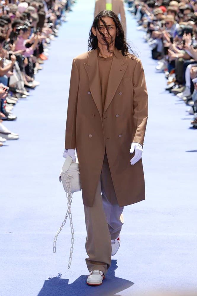 ヴァージル・アブローが手がけた Louis Vuitton 2019年春夏コレクションが遂にお披露目 ファッション界に後世まで語り継がれる歴史的1ページが追加される 〈Louis Vuitton(ルイ ヴィトン)〉がVirgil Abloh(ヴァージル・アブロー)のアーティスティック・ディレクター就任を発表してから早3ヶ月、遂に今をときめくデザイナーの〈LV〉デビューとなる2019年春夏コレクションがお披露目を迎えた。 晴天のパレ・ロワイヤル庭園には、Kanye West(カニエ・ウェスト)とその妻Kim Kardashian(キム・カーダシアン)や、Rihanna(リアーナ)、Kylie Jenner(カイリー・ジェンナー)、A$AP Rocky(エイサップ・ロッキー)、村上隆など、Virgilの友人でもある豪華ゲストが集結。ヒップホップとジャズを繋ぐ成長著しいカルテット、BadBadNotGood(バッドバッドノットグッド)がサウンドトラックを提供したランウェイには、Kid Cudi(キッド・カディ)、Dev Hynes(デヴ・ハインズ)、A$AP Nast(エイサップ・ナスト)、Playboi Carti(プレイボーイ・カルティ)、Theophilus London(テオフィルス・ロンドン)、そして〈Palace(パレス)〉よりLucien Clarke(ルシアン・クラーク)とBlondey McCoy(ブロンディ・マッコイ)らがモデルに起用された。 全56体のルックでは、〈Off-White™️(オフホワイト)〉の党首の真髄である“ラグジュアリーとストリートの融合”が力強さとともに解き放たれた。タイダイ、フローラルパターン、来年80周年を迎える映画『オズの魔法使い』とのコラボレーションなど、必要最小限でありながらも視覚的魅力を放つアイテムがコレクションにエンターテイメント性を付与し、ドラマチックな雰囲気を醸すそのランウェイでは、ルーズフィットのパンツやユーティリティベスト、シアーシャツ、フーディ、仕立ての良いトレンチコートなどがカラーパレットごとに紹介されていく。また、昨日Virgil本人が先行公開したバスケットシューズ風の一足を含め、フットウェアはハイトップシルエットを中心に構成され、上質なドレスシューズもシューレースの配色で遊びをプラス。加えて、〈Louis Vuitton〉の象徴とも言えるラゲージ類は、モノグラムをエンボス加工した半透明の素材やチェーンの斬新な組み合わせにより、良い意味でモードの品格を削ぎ落とした仕上がりにより、観衆の目を釘付けにした。 大喝采の中で迎えたフィナーレではVirgilが涙を流しながら花道を歩き抜け、自身の師匠であるKanyeと熱い抱擁を交わすシーンも。そんな〈Louis Vuitton〉、そしてVirgilの歴史的一幕を是非、上のフォトギャラリーからチェックしてみてはいかがだろうか。