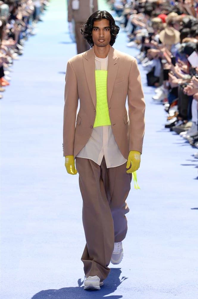 ヴァージル・アブローが手がけた Louis Vuitton 2019年春夏コレクションが遂にお披露目 ファッション界に後世まで語り継がれる歴史的1ページが追加される 〈Louis Vuitton(ルイ ヴィトン)〉がVirgil Abloh(ヴァージル・アブロー)のアーティスティック・ディレクター就任を発表してから早3ヶ月、遂に今をときめくデザイナーの〈LV〉デビューとなる2019年春夏コレクションがお披露目を迎えた。 晴天のパレ・ロワイヤル庭園には、Kanye West(カニエ・ウェスト)とその妻Kim Kardashian(キム・カーダシアン)や、Rihanna(リアーナ)、Kylie Jenner(カイリー・ジェンナー)、A$AP Rocky(エイサップ・ロッキー)、村上隆など、Virgilの友人でもある豪華ゲストが集結。ヒップホップとジャズを繋ぐ成長著しいカルテット、BadBadNotGood(バッドバッドノットグッド)がサウンドトラックを提供したランウェイには、Kid Cudi(キッド・カディ)、Dev Hynes(デヴ・ハインズ)、A$AP Nast(エイサップ・ナスト)、Playboi Carti(プレイボーイ・カルティ)、Theophilus London(テオフィルス・ロンドン)、そして〈Palace(パレス)〉よりLucien Clarke(ルシアン・クラーク)とBlondey McCoy(ブロンディ・マッコイ)らがモデルに起用された。 全56体のルックでは、〈Off-White™️(オフホワイト)〉の党首の真髄である“ラグジュアリーとストリートの融合”が力強さとともに解き放たれた。タイダイ、フローラルパターン、来年80周年を迎える映画『オズの魔法使い』とのコラボレーションなど、必要最小限でありながらも視覚的魅力を放つアイテムがコレクションにエンターテイメント性を付与し、ドラマチックな雰囲気を醸すそのランウェイでは、ルーズフィットのパンツやユーティリティベスト、シアーシャツ、フーディ、仕立ての良いトレンチコートなどがカラーパレットごとに紹介されていく。また、昨日Virgil本人が先行公開したバスケットシューズ風の一足を含め、フットウェアはハイトップシルエットを中心に構成され、上質なドレスシューズもシューレースの配色で遊びをプラス。加えて、〈Louis Vuitton〉の象徴とも言えるラゲージ類は、モノグラムをエンボス加工した半透明の素材やチェーンの斬新な組み合わせにより、良い意味でモードの品格を削ぎ落とした仕上がりにより、観衆の目を釘付けにした。 大喝采の中で迎えたフィナーレではVirgilが涙を流しながら花道を歩き抜け、自身の師匠であるKanyeと熱い抱擁を交わすシーンも。そんな〈Louis Vuitton〉、そしてVirgilの歴史的一幕を是非、上のフォトギャラリーからチェックしてみてはいかがだろうか。