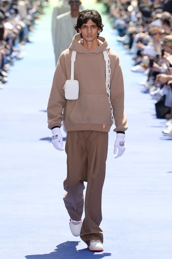 ヴァージル・アブローが手がけた Louis Vuitton 2019年春夏コレクションが遂にお披露目 ファッション界に後世まで語り継がれる歴史的1ページが追加される 〈Louis Vuitton(ルイ ヴィトン)〉がVirgil Abloh(ヴァージル・アブロー)のアーティスティック・ディレクター就任を発表してから早3ヶ月、遂に今をときめくデザイナーの〈LV〉デビューとなる2019年春夏コレクションがお披露目を迎えた。 晴天のパレ・ロワイヤル庭園には、Kanye West(カニエ・ウェスト)とその妻Kim Kardashian(キム・カーダシアン)や、Rihanna(リアーナ)、Kylie Jenner(カイリー・ジェンナー)、A$AP Rocky(エイサップ・ロッキー)、村上隆など、Virgilの友人でもある豪華ゲストが集結。ヒップホップとジャズを繋ぐ成長著しいカルテット、BadBadNotGood(バッドバッドノットグッド)がサウンドトラックを提供したランウェイには、Kid Cudi(キッド・カディ)、Dev Hynes(デヴ・ハインズ)、A$AP Nast(エイサップ・ナスト)、Playboi Carti(プレイボーイ・カルティ)、Theophilus London(テオフィルス・ロンドン)、そして〈Palace(パレス)〉よりLucien Clarke(ルシアン・クラーク)とBlondey McCoy(ブロンディ・マッコイ)らがモデルに起用された。 全56体のルックでは、〈Off-White™️(オフホワイト)〉の党首の真髄である“ラグジュアリーとストリートの融合”が力強さとともに解き放たれた。タイダイ、フローラルパターン、来年80周年を迎える映画『オズの魔法使い』とのコラボレーションなど、必要最小限でありながらも視覚的魅力を放つアイテムがコレクションにエンターテイメント性を付与し、ドラマチックな雰囲気を醸すそのランウェイでは、ルーズフィットのパンツやユーティリティベスト、シアーシャツ、フーディ、仕立ての良いトレンチコートなどがカラーパレットごとに紹介されていく。また、昨日Virgil本人が先行公開したバスケットシューズ風の一足を含め、フットウェアはハイトップシルエットを中心に構成され、上質なドレスシューズもシューレースの配色で遊びをプラス。加えて、〈Louis Vuitton〉の象徴とも言えるラゲージ類は、モノグラムをエンボス加工した半透明の素材やチェーンの斬新な組み合わせにより、良い意味でモードの品格を削ぎ落とした仕上がりにより、観衆の目を釘付けにした。 大喝采の中で迎えたフィナーレではVirgilが涙を流しながら花道を歩き抜け、自身の師匠であるKanyeと熱い抱擁を交わすシーンも。そんな〈Louis Vuitton〉、そしてVirgilの歴史的一幕を是非、上のフォトギャラリーからチェックしてみてはいかがだろうか。