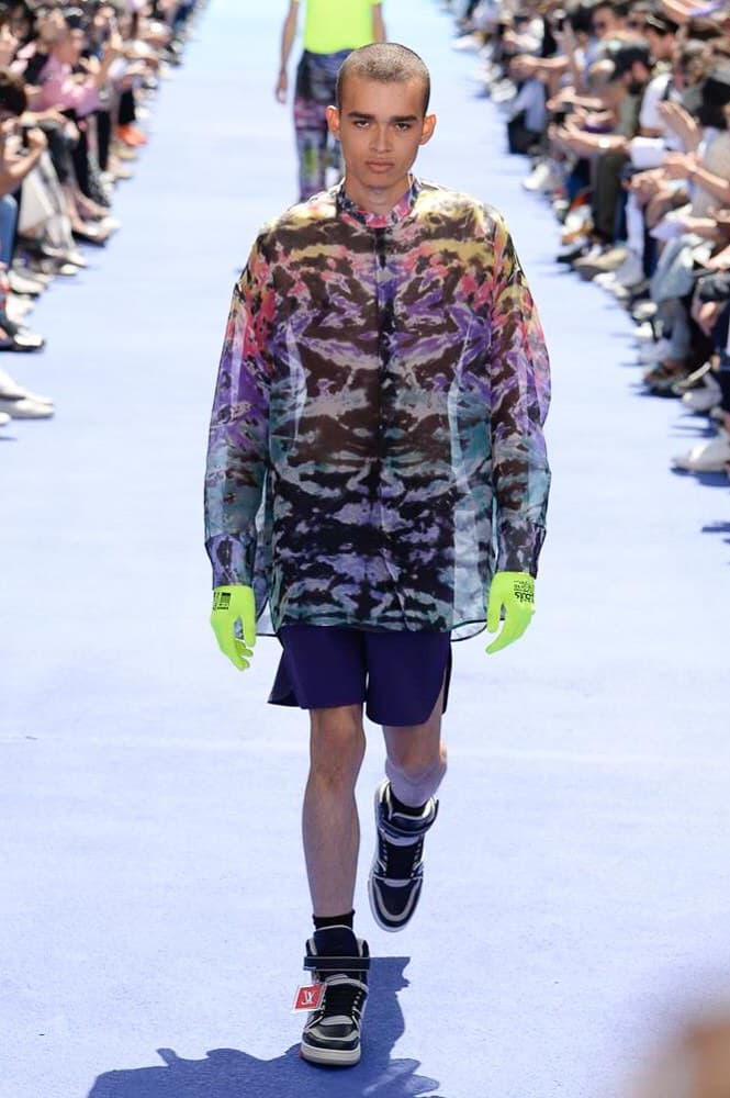 ヴァージル・アブローが手がけた Louis Vuitton 2019年春夏コレクションが遂にお披露目 ファッション界に後世まで語り継がれる歴史的1ページが追加される 〈Louis Vuitton(ルイ ヴィトン)〉がVirgil Abloh(ヴァージル・アブロー)のアーティスティック・ディレクター就任を発表してから早3ヶ月、遂に今をときめくデザイナーの〈LV〉デビューとなる2019年春夏コレクションがお披露目を迎えた。 晴天のパレ・ロワイヤル庭園には、Kanye West(カニエ・ウェスト)とその妻Kim Kardashian(キム・カーダシアン)や、Rihanna(リアーナ)、Kylie Jenner(カイリー・ジェンナー)、A$AP Rocky(エイサップ・ロッキー)、村上隆など、Virgilの友人でもある豪華ゲストが集結。ヒップホップとジャズを繋ぐ成長著しいカルテット、BadBadNotGood(バッドバッドノットグッド)がサウンドトラックを提供したランウェイには、Kid Cudi(キッド・カディ)、Dev Hynes(デヴ・ハインズ)、A$AP Nast(エイサップ・ナスト)、Playboi Carti(プレイボーイ・カルティ)、Theophilus London(テオフィルス・ロンドン)、そして〈Palace(パレス)〉よりLucien Clarke(ルシアン・クラーク)とBlondey McCoy(ブロンディ・マッコイ)らがモデルに起用された。 全56体のルックでは、〈Off-White™️(オフホワイト)〉の党首の真髄である“ラグジュアリーとストリートの融合”が力強さとともに解き放たれた。タイダイ、フローラルパターン、来年80周年を迎える映画『オズの魔法使い』とのコラボレーションなど、必要最小限でありながらも視覚的魅力を放つアイテムがコレクションにエンターテイメント性を付与し、ドラマチックな雰囲気を醸すそのランウェイでは、ルーズフィットのパンツやユーティリティベスト、シアーシャツ、フーディ、仕立ての良いトレンチコートなどがカラーパレットごとに紹介されていく。また、昨日Virgil本人が先行公開したバスケットシューズ風の一足を含め、フットウェアはハイトップシルエットを中心に構成され、上質なドレスシューズもシューレースの配色で遊びをプラス。加えて、〈Louis Vuitton〉の象徴とも言えるラゲージ類は、モノグラムをエンボス加工した半透明の素材やチェーンの斬新な組み合わせにより、良い意味でモードの品格を削ぎ落とした仕上がりにより、観衆の目を釘付けにした。 大喝采の中で迎えたフィナーレではVirgilが涙を流しながら花道を歩き抜け、自身の師匠であるKanyeと熱い抱擁を交わすシーンも。そんな〈Louis Vuitton〉、そしてVirgilの歴史的一幕を是非、上のフォトギャラリーからチェックしてみてはいかがだろうか。