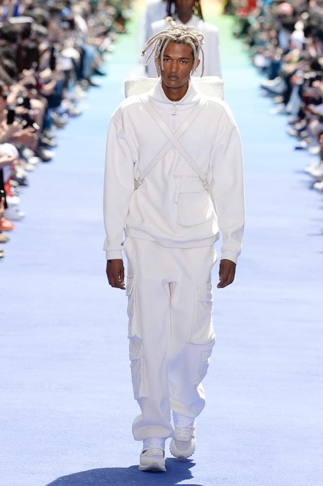 ヴァージル・アブローが手がけた Louis Vuitton 2019年春夏コレクションが遂にお披露目 ファッション界に後世まで語り継がれる歴史的1ページが追加される 〈Louis Vuitton(ルイ ヴィトン)〉がVirgil Abloh(ヴァージル・アブロー)のアーティスティック・ディレクター就任を発表してから早3ヶ月、遂に今をときめくデザイナーの〈LV〉デビューとなる2019年春夏コレクションがお披露目を迎えた。 晴天のパレ・ロワイヤル庭園には、Kanye West(カニエ・ウェスト)とその妻Kim Kardashian(キム・カーダシアン)や、Rihanna(リアーナ)、Kylie Jenner(カイリー・ジェンナー)、A$AP Rocky(エイサップ・ロッキー)、村上隆など、Virgilの友人でもある豪華ゲストが集結。ヒップホップとジャズを繋ぐ成長著しいカルテット、BadBadNotGood(バッドバッドノットグッド)がサウンドトラックを提供したランウェイには、Kid Cudi(キッド・カディ)、Dev Hynes(デヴ・ハインズ)、A$AP Nast(エイサップ・ナスト)、Playboi Carti(プレイボーイ・カルティ)、Theophilus London(テオフィルス・ロンドン)、そして〈Palace(パレス)〉よりLucien Clarke(ルシアン・クラーク)とBlondey McCoy(ブロンディ・マッコイ)らがモデルに起用された。 全56体のルックでは、〈Off-White™️(オフホワイト)〉の党首の真髄である“ラグジュアリーとストリートの融合”が力強さとともに解き放たれた。タイダイ、フローラルパターン、来年80周年を迎える映画『オズの魔法使い』とのコラボレーションなど、必要最小限でありながらも視覚的魅力を放つアイテムがコレクションにエンターテイメント性を付与し、ドラマチックな雰囲気を醸すそのランウェイでは、ルーズフィットのパンツやユーティリティベスト、シアーシャツ、フーディ、仕立ての良いトレンチコートなどがカラーパレットごとに紹介されていく。また、昨日Virgil本人が先行公開したバスケットシューズ風の一足を含め、フットウェアはハイトップシルエットを中心に構成され、上質なドレスシューズもシューレースの配色で遊びをプラス。加えて、〈Louis Vuitton〉の象徴とも言えるラゲージ類は、モノグラムをエンボス加工した半透明の素材やチェーンの斬新な組み合わせにより、良い意味でモードの品格を削ぎ落とした仕上がりにより、観衆の目を釘付けにした。 大喝采の中で迎えたフィナーレではVirgilが涙を流しながら花道を歩き抜け、自身の師匠であるKanyeと熱い抱擁を交わすシーンも。そんな〈Louis Vuitton〉、そしてVirgilの歴史的一幕を是非、上のフォトギャラリーからチェックしてみてはいかがだろうか。