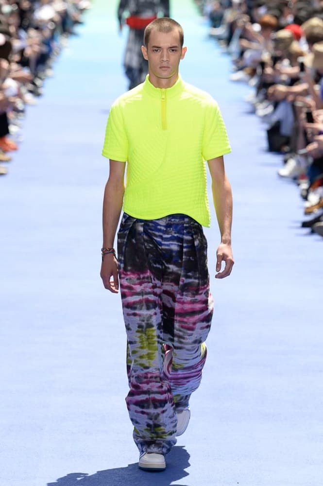 ヴァージル・アブローが手がけた Louis Vuitton 2019年春夏コレクションが遂にお披露目 ファッション界に後世まで語り継がれる歴史的1ページが追加される 〈Louis Vuitton(ルイ ヴィトン)〉がVirgil Abloh(ヴァージル・アブロー)のアーティスティック・ディレクター就任を発表してから早3ヶ月、遂に今をときめくデザイナーの〈LV〉デビューとなる2019年春夏コレクションがお披露目を迎えた。 晴天のパレ・ロワイヤル庭園には、Kanye West(カニエ・ウェスト)とその妻Kim Kardashian(キム・カーダシアン)や、Rihanna(リアーナ)、Kylie Jenner(カイリー・ジェンナー)、A$AP Rocky(エイサップ・ロッキー)、村上隆など、Virgilの友人でもある豪華ゲストが集結。ヒップホップとジャズを繋ぐ成長著しいカルテット、BadBadNotGood(バッドバッドノットグッド)がサウンドトラックを提供したランウェイには、Kid Cudi(キッド・カディ)、Dev Hynes(デヴ・ハインズ)、A$AP Nast(エイサップ・ナスト)、Playboi Carti(プレイボーイ・カルティ)、Theophilus London(テオフィルス・ロンドン)、そして〈Palace(パレス)〉よりLucien Clarke(ルシアン・クラーク)とBlondey McCoy(ブロンディ・マッコイ)らがモデルに起用された。 全56体のルックでは、〈Off-White™️(オフホワイト)〉の党首の真髄である“ラグジュアリーとストリートの融合”が力強さとともに解き放たれた。タイダイ、フローラルパターン、来年80周年を迎える映画『オズの魔法使い』とのコラボレーションなど、必要最小限でありながらも視覚的魅力を放つアイテムがコレクションにエンターテイメント性を付与し、ドラマチックな雰囲気を醸すそのランウェイでは、ルーズフィットのパンツやユーティリティベスト、シアーシャツ、フーディ、仕立ての良いトレンチコートなどがカラーパレットごとに紹介されていく。また、昨日Virgil本人が先行公開したバスケットシューズ風の一足を含め、フットウェアはハイトップシルエットを中心に構成され、上質なドレスシューズもシューレースの配色で遊びをプラス。加えて、〈Louis Vuitton〉の象徴とも言えるラゲージ類は、モノグラムをエンボス加工した半透明の素材やチェーンの斬新な組み合わせにより、良い意味でモードの品格を削ぎ落とした仕上がりにより、観衆の目を釘付けにした。 大喝采の中で迎えたフィナーレではVirgilが涙を流しながら花道を歩き抜け、自身の師匠であるKanyeと熱い抱擁を交わすシーンも。そんな〈Louis Vuitton〉、そしてVirgilの歴史的一幕を是非、上のフォトギャラリーからチェックしてみてはいかがだろうか。