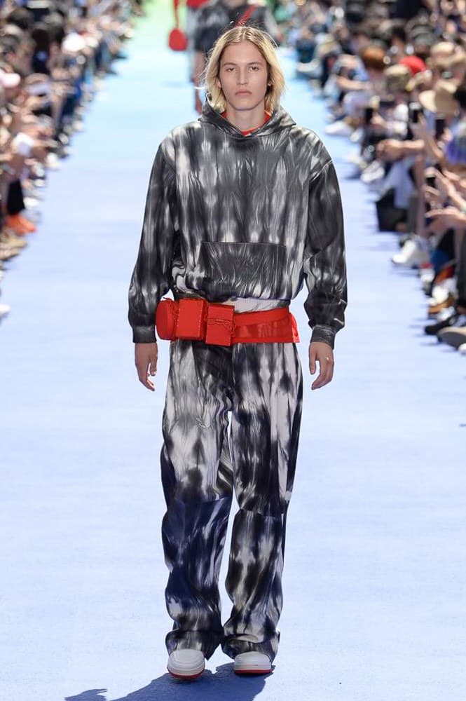 ヴァージル・アブローが手がけた Louis Vuitton 2019年春夏コレクションが遂にお披露目 ファッション界に後世まで語り継がれる歴史的1ページが追加される 〈Louis Vuitton(ルイ ヴィトン)〉がVirgil Abloh(ヴァージル・アブロー)のアーティスティック・ディレクター就任を発表してから早3ヶ月、遂に今をときめくデザイナーの〈LV〉デビューとなる2019年春夏コレクションがお披露目を迎えた。 晴天のパレ・ロワイヤル庭園には、Kanye West(カニエ・ウェスト)とその妻Kim Kardashian(キム・カーダシアン)や、Rihanna(リアーナ)、Kylie Jenner(カイリー・ジェンナー)、A$AP Rocky(エイサップ・ロッキー)、村上隆など、Virgilの友人でもある豪華ゲストが集結。ヒップホップとジャズを繋ぐ成長著しいカルテット、BadBadNotGood(バッドバッドノットグッド)がサウンドトラックを提供したランウェイには、Kid Cudi(キッド・カディ)、Dev Hynes(デヴ・ハインズ)、A$AP Nast(エイサップ・ナスト)、Playboi Carti(プレイボーイ・カルティ)、Theophilus London(テオフィルス・ロンドン)、そして〈Palace(パレス)〉よりLucien Clarke(ルシアン・クラーク)とBlondey McCoy(ブロンディ・マッコイ)らがモデルに起用された。 全56体のルックでは、〈Off-White™️(オフホワイト)〉の党首の真髄である“ラグジュアリーとストリートの融合”が力強さとともに解き放たれた。タイダイ、フローラルパターン、来年80周年を迎える映画『オズの魔法使い』とのコラボレーションなど、必要最小限でありながらも視覚的魅力を放つアイテムがコレクションにエンターテイメント性を付与し、ドラマチックな雰囲気を醸すそのランウェイでは、ルーズフィットのパンツやユーティリティベスト、シアーシャツ、フーディ、仕立ての良いトレンチコートなどがカラーパレットごとに紹介されていく。また、昨日Virgil本人が先行公開したバスケットシューズ風の一足を含め、フットウェアはハイトップシルエットを中心に構成され、上質なドレスシューズもシューレースの配色で遊びをプラス。加えて、〈Louis Vuitton〉の象徴とも言えるラゲージ類は、モノグラムをエンボス加工した半透明の素材やチェーンの斬新な組み合わせにより、良い意味でモードの品格を削ぎ落とした仕上がりにより、観衆の目を釘付けにした。 大喝采の中で迎えたフィナーレではVirgilが涙を流しながら花道を歩き抜け、自身の師匠であるKanyeと熱い抱擁を交わすシーンも。そんな〈Louis Vuitton〉、そしてVirgilの歴史的一幕を是非、上のフォトギャラリーからチェックしてみてはいかがだろうか。