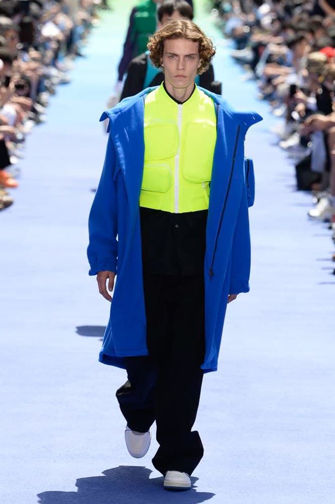ヴァージル・アブローが手がけた Louis Vuitton 2019年春夏コレクションが遂にお披露目 ファッション界に後世まで語り継がれる歴史的1ページが追加される 〈Louis Vuitton(ルイ ヴィトン)〉がVirgil Abloh(ヴァージル・アブロー)のアーティスティック・ディレクター就任を発表してから早3ヶ月、遂に今をときめくデザイナーの〈LV〉デビューとなる2019年春夏コレクションがお披露目を迎えた。 晴天のパレ・ロワイヤル庭園には、Kanye West(カニエ・ウェスト)とその妻Kim Kardashian(キム・カーダシアン)や、Rihanna(リアーナ)、Kylie Jenner(カイリー・ジェンナー)、A$AP Rocky(エイサップ・ロッキー)、村上隆など、Virgilの友人でもある豪華ゲストが集結。ヒップホップとジャズを繋ぐ成長著しいカルテット、BadBadNotGood(バッドバッドノットグッド)がサウンドトラックを提供したランウェイには、Kid Cudi(キッド・カディ)、Dev Hynes(デヴ・ハインズ)、A$AP Nast(エイサップ・ナスト)、Playboi Carti(プレイボーイ・カルティ)、Theophilus London(テオフィルス・ロンドン)、そして〈Palace(パレス)〉よりLucien Clarke(ルシアン・クラーク)とBlondey McCoy(ブロンディ・マッコイ)らがモデルに起用された。 全56体のルックでは、〈Off-White™️(オフホワイト)〉の党首の真髄である“ラグジュアリーとストリートの融合”が力強さとともに解き放たれた。タイダイ、フローラルパターン、来年80周年を迎える映画『オズの魔法使い』とのコラボレーションなど、必要最小限でありながらも視覚的魅力を放つアイテムがコレクションにエンターテイメント性を付与し、ドラマチックな雰囲気を醸すそのランウェイでは、ルーズフィットのパンツやユーティリティベスト、シアーシャツ、フーディ、仕立ての良いトレンチコートなどがカラーパレットごとに紹介されていく。また、昨日Virgil本人が先行公開したバスケットシューズ風の一足を含め、フットウェアはハイトップシルエットを中心に構成され、上質なドレスシューズもシューレースの配色で遊びをプラス。加えて、〈Louis Vuitton〉の象徴とも言えるラゲージ類は、モノグラムをエンボス加工した半透明の素材やチェーンの斬新な組み合わせにより、良い意味でモードの品格を削ぎ落とした仕上がりにより、観衆の目を釘付けにした。 大喝采の中で迎えたフィナーレではVirgilが涙を流しながら花道を歩き抜け、自身の師匠であるKanyeと熱い抱擁を交わすシーンも。そんな〈Louis Vuitton〉、そしてVirgilの歴史的一幕を是非、上のフォトギャラリーからチェックしてみてはいかがだろうか。