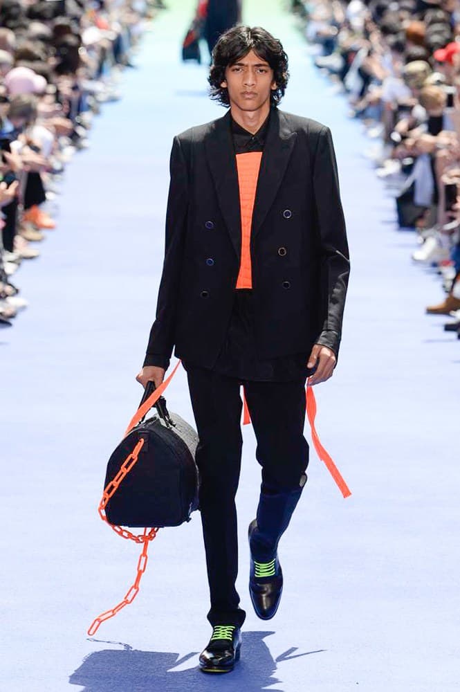 ヴァージル・アブローが手がけた Louis Vuitton 2019年春夏コレクションが遂にお披露目 ファッション界に後世まで語り継がれる歴史的1ページが追加される 〈Louis Vuitton（ルイ ヴィトン）〉がVirgil Abloh（ヴァージル・アブロー）のアーティスティック・ディレクター就任を発表してから早3ヶ月、遂に今をときめくデザイナーの〈LV〉デビューとなる2019年春夏コレクションがお披露目を迎えた。  晴天のパレ・ロワイヤル庭園には、Kanye West（カニエ・ウェスト）とその妻Kim Kardashian（キム・カーダシアン）や、Rihanna（リアーナ）、Kylie Jenner（カイリー・ジェンナー）、A$AP Rocky（エイサップ・ロッキー）、村上隆など、Virgilの友人でもある豪華ゲストが集結。ヒップホップとジャズを繋ぐ成長著しいカルテット、BadBadNotGood（バッドバッドノットグッド）がサウンドトラックを提供したランウェイには、Kid Cudi（キッド・カディ）、Dev Hynes（デヴ・ハインズ）、A$AP Nast（エイサップ・ナスト）、Playboi Carti（プレイボーイ・カルティ）、Theophilus London（テオフィルス・ロンドン）、そして〈Palace（パレス）〉よりLucien Clarke（ルシアン・クラーク）とBlondey McCoy（ブロンディ・マッコイ）らがモデルに起用された。  全56体のルックでは、〈Off-White™️（オフホワイト）〉の党首の真髄である“ラグジュアリーとストリートの融合”が力強さとともに解き放たれた。タイダイ、フローラルパターン、来年80周年を迎える映画『オズの魔法使い』とのコラボレーションなど、必要最小限でありながらも視覚的魅力を放つアイテムがコレクションにエンターテイメント性を付与し、ドラマチックな雰囲気を醸すそのランウェイでは、ルーズフィットのパンツやユーティリティベスト、シアーシャツ、フーディ、仕立ての良いトレンチコートなどがカラーパレットごとに紹介されていく。また、昨日Virgil本人が先行公開したバスケットシューズ風の一足を含め、フットウェアはハイトップシルエットを中心に構成され、上質なドレスシューズもシューレースの配色で遊びをプラス。加えて、〈Louis Vuitton〉の象徴とも言えるラゲージ類は、モノグラムをエンボス加工した半透明の素材やチェーンの斬新な組み合わせにより、良い意味でモードの品格を削ぎ落とした仕上がりにより、観衆の目を釘付けにした。  大喝采の中で迎えたフィナーレではVirgilが涙を流しながら花道を歩き抜け、自身の師匠であるKanyeと熱い抱擁を交わすシーンも。そんな〈Louis Vuitton〉、そしてVirgilの歴史的一幕を是非、上のフォトギャラリーからチェックしてみてはいかがだろうか。