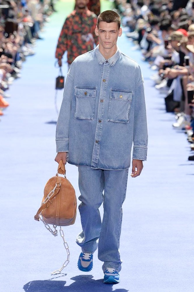 ヴァージル・アブローが手がけた Louis Vuitton 2019年春夏コレクションが遂にお披露目 ファッション界に後世まで語り継がれる歴史的1ページが追加される 〈Louis Vuitton（ルイ ヴィトン）〉がVirgil Abloh（ヴァージル・アブロー）のアーティスティック・ディレクター就任を発表してから早3ヶ月、遂に今をときめくデザイナーの〈LV〉デビューとなる2019年春夏コレクションがお披露目を迎えた。  晴天のパレ・ロワイヤル庭園には、Kanye West（カニエ・ウェスト）とその妻Kim Kardashian（キム・カーダシアン）や、Rihanna（リアーナ）、Kylie Jenner（カイリー・ジェンナー）、A$AP Rocky（エイサップ・ロッキー）、村上隆など、Virgilの友人でもある豪華ゲストが集結。ヒップホップとジャズを繋ぐ成長著しいカルテット、BadBadNotGood（バッドバッドノットグッド）がサウンドトラックを提供したランウェイには、Kid Cudi（キッド・カディ）、Dev Hynes（デヴ・ハインズ）、A$AP Nast（エイサップ・ナスト）、Playboi Carti（プレイボーイ・カルティ）、Theophilus London（テオフィルス・ロンドン）、そして〈Palace（パレス）〉よりLucien Clarke（ルシアン・クラーク）とBlondey McCoy（ブロンディ・マッコイ）らがモデルに起用された。  全56体のルックでは、〈Off-White™️（オフホワイト）〉の党首の真髄である“ラグジュアリーとストリートの融合”が力強さとともに解き放たれた。タイダイ、フローラルパターン、来年80周年を迎える映画『オズの魔法使い』とのコラボレーションなど、必要最小限でありながらも視覚的魅力を放つアイテムがコレクションにエンターテイメント性を付与し、ドラマチックな雰囲気を醸すそのランウェイでは、ルーズフィットのパンツやユーティリティベスト、シアーシャツ、フーディ、仕立ての良いトレンチコートなどがカラーパレットごとに紹介されていく。また、昨日Virgil本人が先行公開したバスケットシューズ風の一足を含め、フットウェアはハイトップシルエットを中心に構成され、上質なドレスシューズもシューレースの配色で遊びをプラス。加えて、〈Louis Vuitton〉の象徴とも言えるラゲージ類は、モノグラムをエンボス加工した半透明の素材やチェーンの斬新な組み合わせにより、良い意味でモードの品格を削ぎ落とした仕上がりにより、観衆の目を釘付けにした。  大喝采の中で迎えたフィナーレではVirgilが涙を流しながら花道を歩き抜け、自身の師匠であるKanyeと熱い抱擁を交わすシーンも。そんな〈Louis Vuitton〉、そしてVirgilの歴史的一幕を是非、上のフォトギャラリーからチェックしてみてはいかがだろうか。