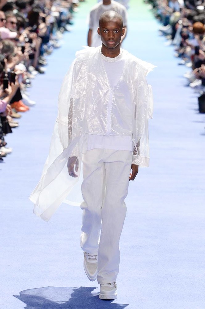 ヴァージル・アブローが手がけた Louis Vuitton 2019年春夏コレクションが遂にお披露目 ファッション界に後世まで語り継がれる歴史的1ページが追加される 〈Louis Vuitton（ルイ ヴィトン）〉がVirgil Abloh（ヴァージル・アブロー）のアーティスティック・ディレクター就任を発表してから早3ヶ月、遂に今をときめくデザイナーの〈LV〉デビューとなる2019年春夏コレクションがお披露目を迎えた。  晴天のパレ・ロワイヤル庭園には、Kanye West（カニエ・ウェスト）とその妻Kim Kardashian（キム・カーダシアン）や、Rihanna（リアーナ）、Kylie Jenner（カイリー・ジェンナー）、A$AP Rocky（エイサップ・ロッキー）、村上隆など、Virgilの友人でもある豪華ゲストが集結。ヒップホップとジャズを繋ぐ成長著しいカルテット、BadBadNotGood（バッドバッドノットグッド）がサウンドトラックを提供したランウェイには、Kid Cudi（キッド・カディ）、Dev Hynes（デヴ・ハインズ）、A$AP Nast（エイサップ・ナスト）、Playboi Carti（プレイボーイ・カルティ）、Theophilus London（テオフィルス・ロンドン）、そして〈Palace（パレス）〉よりLucien Clarke（ルシアン・クラーク）とBlondey McCoy（ブロンディ・マッコイ）らがモデルに起用された。  全56体のルックでは、〈Off-White™️（オフホワイト）〉の党首の真髄である“ラグジュアリーとストリートの融合”が力強さとともに解き放たれた。タイダイ、フローラルパターン、来年80周年を迎える映画『オズの魔法使い』とのコラボレーションなど、必要最小限でありながらも視覚的魅力を放つアイテムがコレクションにエンターテイメント性を付与し、ドラマチックな雰囲気を醸すそのランウェイでは、ルーズフィットのパンツやユーティリティベスト、シアーシャツ、フーディ、仕立ての良いトレンチコートなどがカラーパレットごとに紹介されていく。また、昨日Virgil本人が先行公開したバスケットシューズ風の一足を含め、フットウェアはハイトップシルエットを中心に構成され、上質なドレスシューズもシューレースの配色で遊びをプラス。加えて、〈Louis Vuitton〉の象徴とも言えるラゲージ類は、モノグラムをエンボス加工した半透明の素材やチェーンの斬新な組み合わせにより、良い意味でモードの品格を削ぎ落とした仕上がりにより、観衆の目を釘付けにした。  大喝采の中で迎えたフィナーレではVirgilが涙を流しながら花道を歩き抜け、自身の師匠であるKanyeと熱い抱擁を交わすシーンも。そんな〈Louis Vuitton〉、そしてVirgilの歴史的一幕を是非、上のフォトギャラリーからチェックしてみてはいかがだろうか。