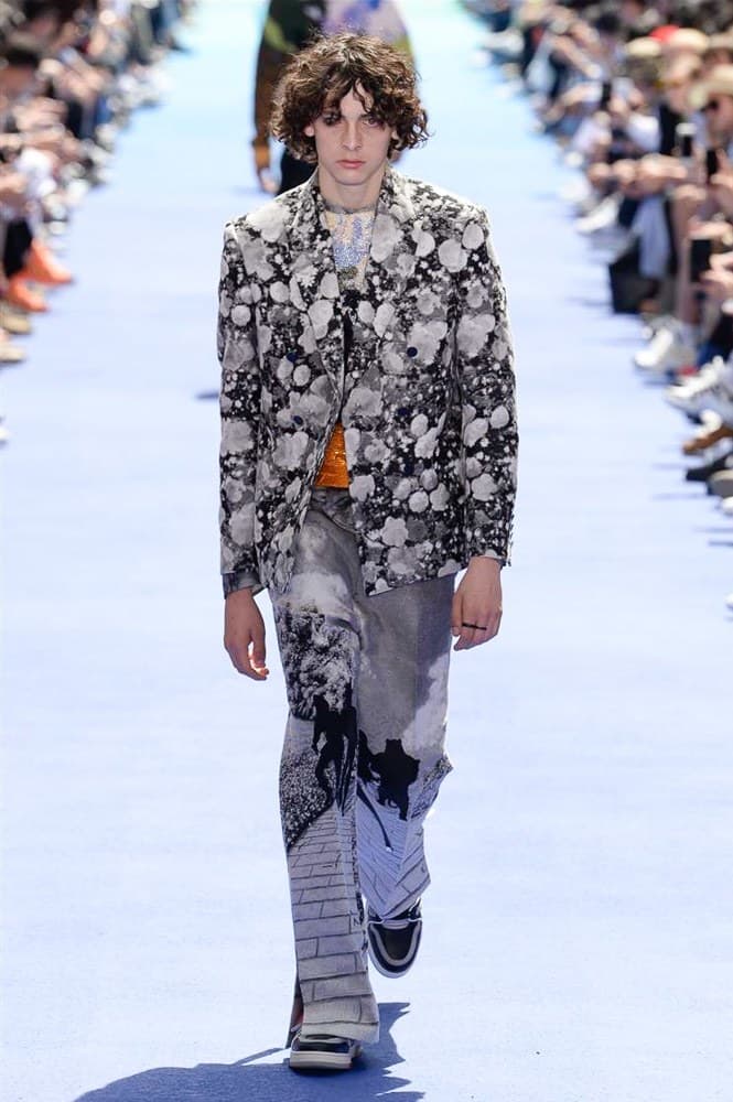 ヴァージル・アブローが手がけた Louis Vuitton 2019年春夏コレクションが遂にお披露目 ファッション界に後世まで語り継がれる歴史的1ページが追加される 〈Louis Vuitton(ルイ ヴィトン)〉がVirgil Abloh(ヴァージル・アブロー)のアーティスティック・ディレクター就任を発表してから早3ヶ月、遂に今をときめくデザイナーの〈LV〉デビューとなる2019年春夏コレクションがお披露目を迎えた。 晴天のパレ・ロワイヤル庭園には、Kanye West(カニエ・ウェスト)とその妻Kim Kardashian(キム・カーダシアン)や、Rihanna(リアーナ)、Kylie Jenner(カイリー・ジェンナー)、A$AP Rocky(エイサップ・ロッキー)、村上隆など、Virgilの友人でもある豪華ゲストが集結。ヒップホップとジャズを繋ぐ成長著しいカルテット、BadBadNotGood(バッドバッドノットグッド)がサウンドトラックを提供したランウェイには、Kid Cudi(キッド・カディ)、Dev Hynes(デヴ・ハインズ)、A$AP Nast(エイサップ・ナスト)、Playboi Carti(プレイボーイ・カルティ)、Theophilus London(テオフィルス・ロンドン)、そして〈Palace(パレス)〉よりLucien Clarke(ルシアン・クラーク)とBlondey McCoy(ブロンディ・マッコイ)らがモデルに起用された。 全56体のルックでは、〈Off-White™️(オフホワイト)〉の党首の真髄である“ラグジュアリーとストリートの融合”が力強さとともに解き放たれた。タイダイ、フローラルパターン、来年80周年を迎える映画『オズの魔法使い』とのコラボレーションなど、必要最小限でありながらも視覚的魅力を放つアイテムがコレクションにエンターテイメント性を付与し、ドラマチックな雰囲気を醸すそのランウェイでは、ルーズフィットのパンツやユーティリティベスト、シアーシャツ、フーディ、仕立ての良いトレンチコートなどがカラーパレットごとに紹介されていく。また、昨日Virgil本人が先行公開したバスケットシューズ風の一足を含め、フットウェアはハイトップシルエットを中心に構成され、上質なドレスシューズもシューレースの配色で遊びをプラス。加えて、〈Louis Vuitton〉の象徴とも言えるラゲージ類は、モノグラムをエンボス加工した半透明の素材やチェーンの斬新な組み合わせにより、良い意味でモードの品格を削ぎ落とした仕上がりにより、観衆の目を釘付けにした。 大喝采の中で迎えたフィナーレではVirgilが涙を流しながら花道を歩き抜け、自身の師匠であるKanyeと熱い抱擁を交わすシーンも。そんな〈Louis Vuitton〉、そしてVirgilの歴史的一幕を是非、上のフォトギャラリーからチェックしてみてはいかがだろうか。