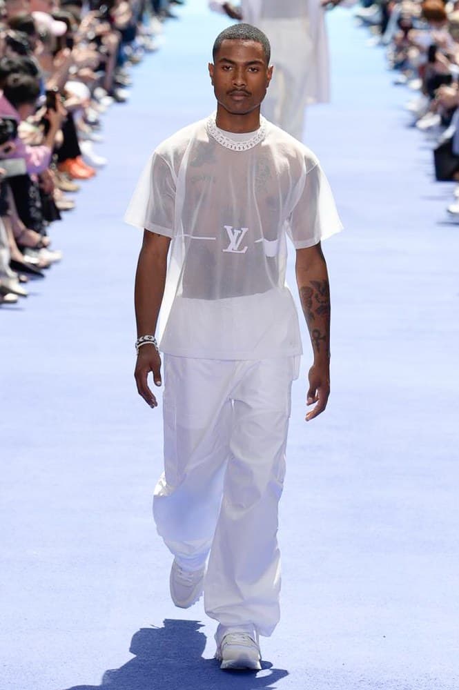 ヴァージル・アブローが手がけた Louis Vuitton 2019年春夏コレクションが遂にお披露目 ファッション界に後世まで語り継がれる歴史的1ページが追加される 〈Louis Vuitton(ルイ ヴィトン)〉がVirgil Abloh(ヴァージル・アブロー)のアーティスティック・ディレクター就任を発表してから早3ヶ月、遂に今をときめくデザイナーの〈LV〉デビューとなる2019年春夏コレクションがお披露目を迎えた。 晴天のパレ・ロワイヤル庭園には、Kanye West(カニエ・ウェスト)とその妻Kim Kardashian(キム・カーダシアン)や、Rihanna(リアーナ)、Kylie Jenner(カイリー・ジェンナー)、A$AP Rocky(エイサップ・ロッキー)、村上隆など、Virgilの友人でもある豪華ゲストが集結。ヒップホップとジャズを繋ぐ成長著しいカルテット、BadBadNotGood(バッドバッドノットグッド)がサウンドトラックを提供したランウェイには、Kid Cudi(キッド・カディ)、Dev Hynes(デヴ・ハインズ)、A$AP Nast(エイサップ・ナスト)、Playboi Carti(プレイボーイ・カルティ)、Theophilus London(テオフィルス・ロンドン)、そして〈Palace(パレス)〉よりLucien Clarke(ルシアン・クラーク)とBlondey McCoy(ブロンディ・マッコイ)らがモデルに起用された。 全56体のルックでは、〈Off-White™️(オフホワイト)〉の党首の真髄である“ラグジュアリーとストリートの融合”が力強さとともに解き放たれた。タイダイ、フローラルパターン、来年80周年を迎える映画『オズの魔法使い』とのコラボレーションなど、必要最小限でありながらも視覚的魅力を放つアイテムがコレクションにエンターテイメント性を付与し、ドラマチックな雰囲気を醸すそのランウェイでは、ルーズフィットのパンツやユーティリティベスト、シアーシャツ、フーディ、仕立ての良いトレンチコートなどがカラーパレットごとに紹介されていく。また、昨日Virgil本人が先行公開したバスケットシューズ風の一足を含め、フットウェアはハイトップシルエットを中心に構成され、上質なドレスシューズもシューレースの配色で遊びをプラス。加えて、〈Louis Vuitton〉の象徴とも言えるラゲージ類は、モノグラムをエンボス加工した半透明の素材やチェーンの斬新な組み合わせにより、良い意味でモードの品格を削ぎ落とした仕上がりにより、観衆の目を釘付けにした。 大喝采の中で迎えたフィナーレではVirgilが涙を流しながら花道を歩き抜け、自身の師匠であるKanyeと熱い抱擁を交わすシーンも。そんな〈Louis Vuitton〉、そしてVirgilの歴史的一幕を是非、上のフォトギャラリーからチェックしてみてはいかがだろうか。