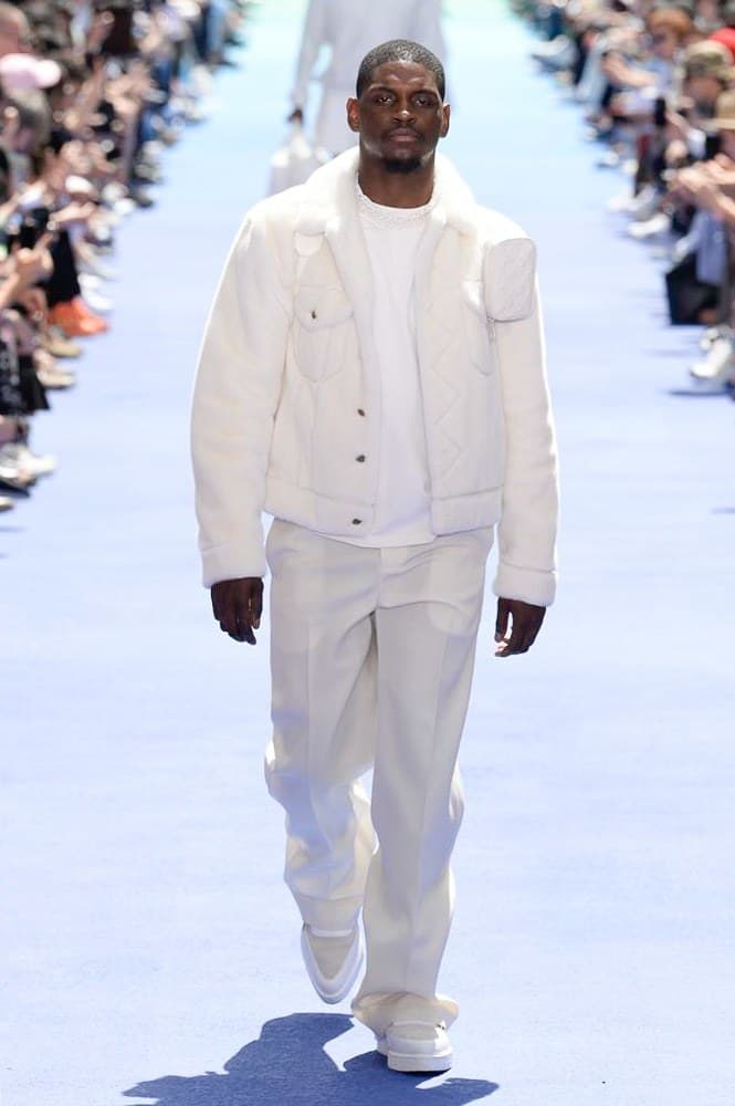 ヴァージル・アブローが手がけた Louis Vuitton 2019年春夏コレクションが遂にお披露目 ファッション界に後世まで語り継がれる歴史的1ページが追加される 〈Louis Vuitton(ルイ ヴィトン)〉がVirgil Abloh(ヴァージル・アブロー)のアーティスティック・ディレクター就任を発表してから早3ヶ月、遂に今をときめくデザイナーの〈LV〉デビューとなる2019年春夏コレクションがお披露目を迎えた。 晴天のパレ・ロワイヤル庭園には、Kanye West(カニエ・ウェスト)とその妻Kim Kardashian(キム・カーダシアン)や、Rihanna(リアーナ)、Kylie Jenner(カイリー・ジェンナー)、A$AP Rocky(エイサップ・ロッキー)、村上隆など、Virgilの友人でもある豪華ゲストが集結。ヒップホップとジャズを繋ぐ成長著しいカルテット、BadBadNotGood(バッドバッドノットグッド)がサウンドトラックを提供したランウェイには、Kid Cudi(キッド・カディ)、Dev Hynes(デヴ・ハインズ)、A$AP Nast(エイサップ・ナスト)、Playboi Carti(プレイボーイ・カルティ)、Theophilus London(テオフィルス・ロンドン)、そして〈Palace(パレス)〉よりLucien Clarke(ルシアン・クラーク)とBlondey McCoy(ブロンディ・マッコイ)らがモデルに起用された。 全56体のルックでは、〈Off-White™️(オフホワイト)〉の党首の真髄である“ラグジュアリーとストリートの融合”が力強さとともに解き放たれた。タイダイ、フローラルパターン、来年80周年を迎える映画『オズの魔法使い』とのコラボレーションなど、必要最小限でありながらも視覚的魅力を放つアイテムがコレクションにエンターテイメント性を付与し、ドラマチックな雰囲気を醸すそのランウェイでは、ルーズフィットのパンツやユーティリティベスト、シアーシャツ、フーディ、仕立ての良いトレンチコートなどがカラーパレットごとに紹介されていく。また、昨日Virgil本人が先行公開したバスケットシューズ風の一足を含め、フットウェアはハイトップシルエットを中心に構成され、上質なドレスシューズもシューレースの配色で遊びをプラス。加えて、〈Louis Vuitton〉の象徴とも言えるラゲージ類は、モノグラムをエンボス加工した半透明の素材やチェーンの斬新な組み合わせにより、良い意味でモードの品格を削ぎ落とした仕上がりにより、観衆の目を釘付けにした。 大喝采の中で迎えたフィナーレではVirgilが涙を流しながら花道を歩き抜け、自身の師匠であるKanyeと熱い抱擁を交わすシーンも。そんな〈Louis Vuitton〉、そしてVirgilの歴史的一幕を是非、上のフォトギャラリーからチェックしてみてはいかがだろうか。