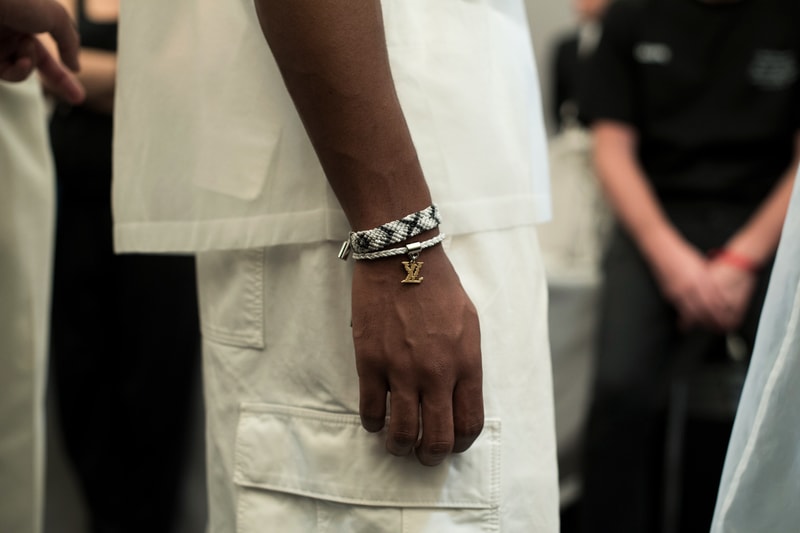 ヴァージル・アブローのビジョンを体現した Louis Vuitton 2019年春夏コレクションのバックステージに潜入 ランウェイルックからは確認することのできない各種アパレル&アクセサリーのディテールを撮影することに成功した服好き必見のフォトセット Virgil Abloh(ヴァージル・アブロー)は、〈Louis Vuitton(ルイ ヴィトン)〉のアーティスティックデザイナー就任後初のランウェイをパリのパレ・ロワイヤル庭園で披露した。歴史的一幕で、今をときめくイリノイ州出身のデザイナーは〈LV〉に未だかつて見たことのない景色を見せたと言っても過言ではないだろう。だが、そのクリエイションの真髄は、バックステージでこそ痛感するものだった。 ベストやポロシャツなどに見られる3Dのジオメトリックパターンで立体感を演出したレイヤード、モノグラムの花型のカフスボタン、大胆な原色使いなど、Virgilは〈Louis Vuitton〉のDNAを従来とは異なるアプローチで体現。また、セーター、スーツ、フーディといったメンズウェアも前衛的なカッティングとステッチワークで新鮮味が付与されると同時に、組み込み式のポーチやジッパー、プルタブなどを応用することで、壮麗なデザインの中にカジュアル/アウトドアウェアに着想を得た機能性を追加している。その一方で、ハイカットシルエットを中心に構成されたスニーカーは、Air Jordanや〈Ewing Athletics(ユーイング アスレチックス)〉などのバスケットシューズを原型に、今後の展開に自然と期待が膨らむデザインのものが数多く出揃った印象だ。そして、言及せずには終われないアクセサリーコレクションだが、ラゲージについてはまさに“型破り”という言葉がよく似合う。Kim Jones(キム・ジョーンズ)政権の頃から変革が見え隠れしたが、建築デザインを背景に持つVirgilが加わったことで、クラシカルなシルエットは全く別物のような表情へと生まれ変わっている。 ランウェイルックからは確認することのできない各プロダクトのディテールワークを是非、上のフォトギャラリーからチェックしてみてほしい。あわせて、本ランウェイのハイライトとも言えるVirgilとKanye West(カニエ・ウェスト)が涙ながらに抱擁しあう感動の1シーンもお見逃しなく。
