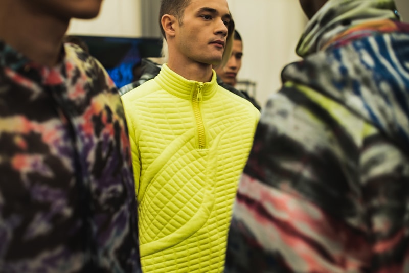 ヴァージル・アブローのビジョンを体現した Louis Vuitton 2019年春夏コレクションのバックステージに潜入 ランウェイルックからは確認することのできない各種アパレル&アクセサリーのディテールを撮影することに成功した服好き必見のフォトセット Virgil Abloh(ヴァージル・アブロー)は、〈Louis Vuitton(ルイ ヴィトン)〉のアーティスティックデザイナー就任後初のランウェイをパリのパレ・ロワイヤル庭園で披露した。歴史的一幕で、今をときめくイリノイ州出身のデザイナーは〈LV〉に未だかつて見たことのない景色を見せたと言っても過言ではないだろう。だが、そのクリエイションの真髄は、バックステージでこそ痛感するものだった。 ベストやポロシャツなどに見られる3Dのジオメトリックパターンで立体感を演出したレイヤード、モノグラムの花型のカフスボタン、大胆な原色使いなど、Virgilは〈Louis Vuitton〉のDNAを従来とは異なるアプローチで体現。また、セーター、スーツ、フーディといったメンズウェアも前衛的なカッティングとステッチワークで新鮮味が付与されると同時に、組み込み式のポーチやジッパー、プルタブなどを応用することで、壮麗なデザインの中にカジュアル/アウトドアウェアに着想を得た機能性を追加している。その一方で、ハイカットシルエットを中心に構成されたスニーカーは、Air Jordanや〈Ewing Athletics(ユーイング アスレチックス)〉などのバスケットシューズを原型に、今後の展開に自然と期待が膨らむデザインのものが数多く出揃った印象だ。そして、言及せずには終われないアクセサリーコレクションだが、ラゲージについてはまさに“型破り”という言葉がよく似合う。Kim Jones(キム・ジョーンズ)政権の頃から変革が見え隠れしたが、建築デザインを背景に持つVirgilが加わったことで、クラシカルなシルエットは全く別物のような表情へと生まれ変わっている。 ランウェイルックからは確認することのできない各プロダクトのディテールワークを是非、上のフォトギャラリーからチェックしてみてほしい。あわせて、本ランウェイのハイライトとも言えるVirgilとKanye West(カニエ・ウェスト)が涙ながらに抱擁しあう感動の1シーンもお見逃しなく。