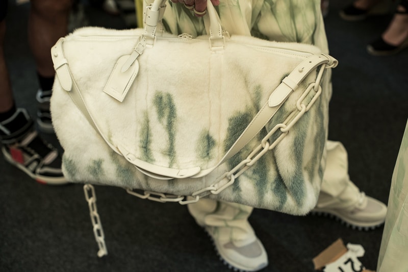 ヴァージル・アブローのビジョンを体現した Louis Vuitton 2019年春夏コレクションのバックステージに潜入 ランウェイルックからは確認することのできない各種アパレル&アクセサリーのディテールを撮影することに成功した服好き必見のフォトセット Virgil Abloh(ヴァージル・アブロー)は、〈Louis Vuitton(ルイ ヴィトン)〉のアーティスティックデザイナー就任後初のランウェイをパリのパレ・ロワイヤル庭園で披露した。歴史的一幕で、今をときめくイリノイ州出身のデザイナーは〈LV〉に未だかつて見たことのない景色を見せたと言っても過言ではないだろう。だが、そのクリエイションの真髄は、バックステージでこそ痛感するものだった。 ベストやポロシャツなどに見られる3Dのジオメトリックパターンで立体感を演出したレイヤード、モノグラムの花型のカフスボタン、大胆な原色使いなど、Virgilは〈Louis Vuitton〉のDNAを従来とは異なるアプローチで体現。また、セーター、スーツ、フーディといったメンズウェアも前衛的なカッティングとステッチワークで新鮮味が付与されると同時に、組み込み式のポーチやジッパー、プルタブなどを応用することで、壮麗なデザインの中にカジュアル/アウトドアウェアに着想を得た機能性を追加している。その一方で、ハイカットシルエットを中心に構成されたスニーカーは、Air Jordanや〈Ewing Athletics(ユーイング アスレチックス)〉などのバスケットシューズを原型に、今後の展開に自然と期待が膨らむデザインのものが数多く出揃った印象だ。そして、言及せずには終われないアクセサリーコレクションだが、ラゲージについてはまさに“型破り”という言葉がよく似合う。Kim Jones(キム・ジョーンズ)政権の頃から変革が見え隠れしたが、建築デザインを背景に持つVirgilが加わったことで、クラシカルなシルエットは全く別物のような表情へと生まれ変わっている。 ランウェイルックからは確認することのできない各プロダクトのディテールワークを是非、上のフォトギャラリーからチェックしてみてほしい。あわせて、本ランウェイのハイライトとも言えるVirgilとKanye West(カニエ・ウェスト)が涙ながらに抱擁しあう感動の1シーンもお見逃しなく。