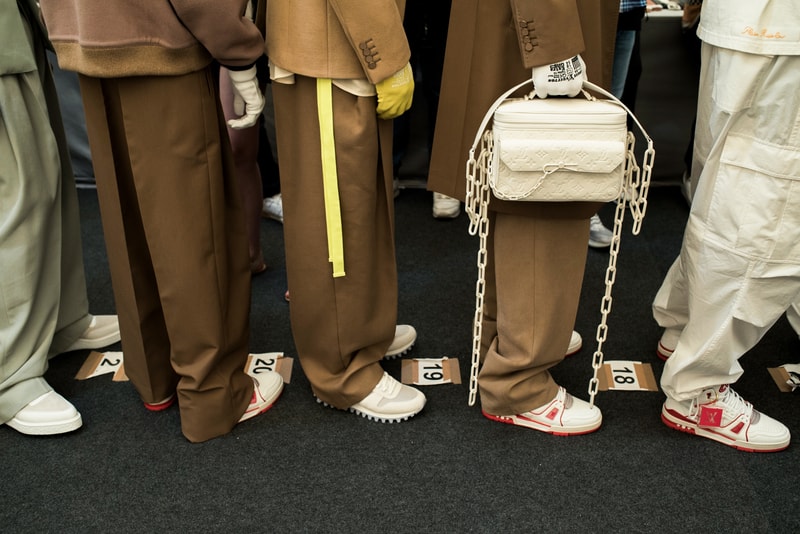 ヴァージル・アブローのビジョンを体現した Louis Vuitton 2019年春夏コレクションのバックステージに潜入 ランウェイルックからは確認することのできない各種アパレル&アクセサリーのディテールを撮影することに成功した服好き必見のフォトセット Virgil Abloh(ヴァージル・アブロー)は、〈Louis Vuitton(ルイ ヴィトン)〉のアーティスティックデザイナー就任後初のランウェイをパリのパレ・ロワイヤル庭園で披露した。歴史的一幕で、今をときめくイリノイ州出身のデザイナーは〈LV〉に未だかつて見たことのない景色を見せたと言っても過言ではないだろう。だが、そのクリエイションの真髄は、バックステージでこそ痛感するものだった。 ベストやポロシャツなどに見られる3Dのジオメトリックパターンで立体感を演出したレイヤード、モノグラムの花型のカフスボタン、大胆な原色使いなど、Virgilは〈Louis Vuitton〉のDNAを従来とは異なるアプローチで体現。また、セーター、スーツ、フーディといったメンズウェアも前衛的なカッティングとステッチワークで新鮮味が付与されると同時に、組み込み式のポーチやジッパー、プルタブなどを応用することで、壮麗なデザインの中にカジュアル/アウトドアウェアに着想を得た機能性を追加している。その一方で、ハイカットシルエットを中心に構成されたスニーカーは、Air Jordanや〈Ewing Athletics(ユーイング アスレチックス)〉などのバスケットシューズを原型に、今後の展開に自然と期待が膨らむデザインのものが数多く出揃った印象だ。そして、言及せずには終われないアクセサリーコレクションだが、ラゲージについてはまさに“型破り”という言葉がよく似合う。Kim Jones(キム・ジョーンズ)政権の頃から変革が見え隠れしたが、建築デザインを背景に持つVirgilが加わったことで、クラシカルなシルエットは全く別物のような表情へと生まれ変わっている。 ランウェイルックからは確認することのできない各プロダクトのディテールワークを是非、上のフォトギャラリーからチェックしてみてほしい。あわせて、本ランウェイのハイライトとも言えるVirgilとKanye West(カニエ・ウェスト)が涙ながらに抱擁しあう感動の1シーンもお見逃しなく。