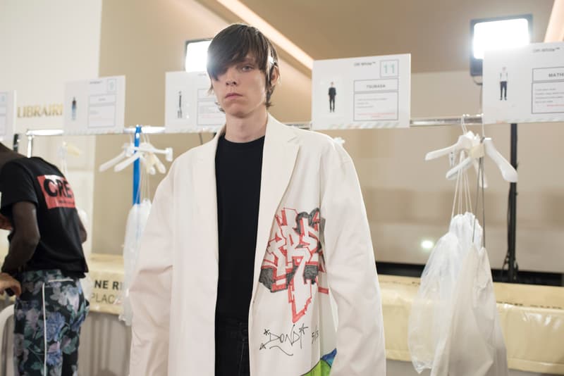 Off-White™ 2019年春夏コレクションのバックステージに潜入 〈Nike〉とのコラボレーション継続を確約する初見のAir Max 97も確認 Virgil Abloh(ヴァージル・アブロー)がパリファッションウィーク期間中に発表した〈Off-White™(オフホワイト)〉の2019年春夏コレクションは、1980〜90年代のアメリカのユースカルチャーを現代的に解釈すると同時に、Futura(フューチュラ)などにも多大な影響を与えたイーストブルックリンの伝説のグラフィティーライター、Dondi White(ドンディ・ホワイト)にトリビュートを捧げるものだった。 『HYPEBEAST』はこの文化的背景を感じさせるランウェイの舞台裏に潜入。コレクションでは“DONDI”の名を配したTシャツのほか、“Style Master”の異名を持つ彼の作風にオマージュを捧げるグラフィティを随所で確認。また、コレクションの中核をなすデニムピースもスカルモチーフやウィットに富んだリング使い、ダメージ/ペイント加工など、細部にまで一切の抜かりがなく、『ザ・シンプソンズ』のバートがフロントを飾るニットやTシャツはまさに90’sの象徴のひとつであるキャラクターものの最たる例だろう。 一方で、〈Nike(ナイキ)〉とのコラボレーションからも初見のスニーカーがベールを脱いだ。ベースに採用したのは、Air Max 97。グレーのアッパーはシームレスな仕上がりで、サイドにはグラデーションのスウッシュをセットしたものも。どのタイミングでのリリースになるのかは〈Nike〉からのアップデートを待つ必要がありそうだが、両者の関係はまだまだ継続路線と見ていいだろう。 〈Off-White™〉の2019年春夏コレクションの全貌を解明するバックステージフォトは、上のフォトギャラリーから。あわせて、同コレクションのランウェイルックもお見逃しなく。
