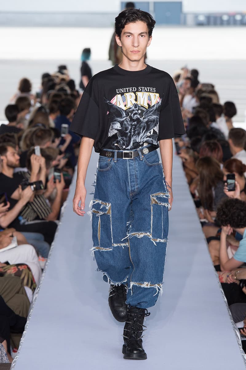 戦争で刻まれた恐怖心と怒りを投影した Vetements 2019年春夏コレクション デムナの母国である現ジョージアとロシア連邦間の紛争をテーマに採用 Demna Gvasalia デムナ・ヴァザリア Vetements ヴェトモン グルジア ジョージア 南オセチア紛争 グラフィックフーディ Tシャツ フィールドジャケット カーゴパンツ トゲを配したハイカットブーツ Reebok リーボック HYPEBEAST ハイプビースト