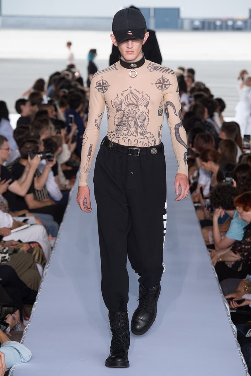 戦争で刻まれた恐怖心と怒りを投影した Vetements 2019年春夏コレクション デムナの母国である現ジョージアとロシア連邦間の紛争をテーマに採用 Demna Gvasalia デムナ・ヴァザリア Vetements ヴェトモン グルジア ジョージア 南オセチア紛争 グラフィックフーディ Tシャツ フィールドジャケット カーゴパンツ トゲを配したハイカットブーツ Reebok リーボック HYPEBEAST ハイプビースト