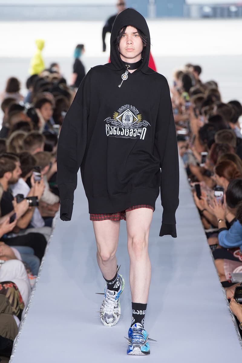 戦争で刻まれた恐怖心と怒りを投影した Vetements 2019年春夏コレクション デムナの母国である現ジョージアとロシア連邦間の紛争をテーマに採用 Demna Gvasalia デムナ・ヴァザリア Vetements ヴェトモン グルジア ジョージア 南オセチア紛争 グラフィックフーディ Tシャツ フィールドジャケット カーゴパンツ トゲを配したハイカットブーツ Reebok リーボック HYPEBEAST ハイプビースト