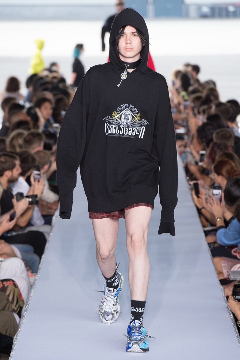戦争で刻まれた恐怖心と怒りを投影した Vetements 2019年春夏コレクション デムナの母国である現ジョージアとロシア連邦間の紛争をテーマに採用 Demna Gvasalia デムナ・ヴァザリア Vetements ヴェトモン グルジア ジョージア 南オセチア紛争 グラフィックフーディ Tシャツ フィールドジャケット カーゴパンツ トゲを配したハイカットブーツ Reebok リーボック HYPEBEAST ハイプビースト