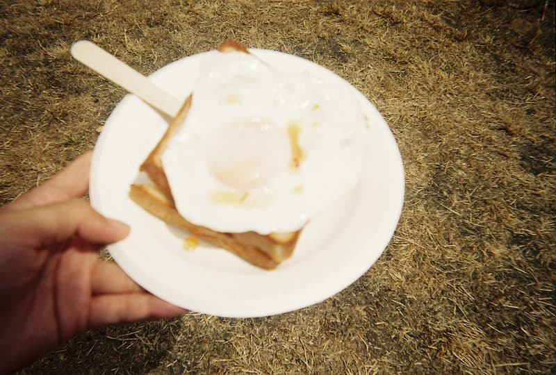Back to Film:HYPEBEAST 編集部の等身大 FUJI ROCK FESTIVAL '18 備忘録 ファッション業界の方々から学生時代の部活の先輩まで、『HYPEBEAST』のリアルな日常を使い捨てカメラで記録した「FUJI ROCK」の番外編企画 山の天気は変わりやすい。「FUJI ROCK FESTIVAL '18」の会場となった苗場スキー場は途中に台風の通過もあってか、激しい雨と燦々と降り注ぐ日照りの繰り返しで、どこかの先人が作った言葉の意味を再認識した3日間だった。『HYPEBEAST』では連日、臨場感溢れるアーティストのステージパフォーマンスを中心とした速報や、タフな環境下でもファッション>機能性のマインドを持ち合わせる人々を撮影したストリートスナップをご紹介してきた。これらの記事制作の背景に少しだけ触れると、取材は日中から場合によっては深夜にまで及び、翌日朝は写真の編集と記事の執筆、現場では聴きたいアーティストのライブを余裕綽々で堪能できる時間はほとんどなく、山道の移動と悪天候がプレゼントしてくれる疲労の蓄積で、夜はホテルに戻るや否や汗を流し、次の日に備えて寝る、これがリアルである。 しかし、移動の最中や束の間の休憩中に遭遇する、日頃からお世話になっているファッション/音楽業界の方々、夜遊び仲間、中学時代の部活の先輩、久しぶりに会った音好きの友人たちと言い合うライブの感想、たわいもない会話、そしてビールでの乾杯は、編集部にとっては紛れもない「FUJI ROCK」の醍醐味なのだ。 そこで、我々は本気の仕事の裏側で、ポケットに使い捨てカメラを忍ばせ、柵前の景色から美味しいご飯を提供してくれたお食事処の皆さんまで、実際にいたロケーションと遭遇した仕事仲間&友人を気の向くままにパシャパシャと撮影。このカジュアルな企画では、上原のセレクトショップ『UFO(UPPER FIELD ONE)』の千寿公久、過去に#Essentialsに登場してくれた『Mastered』編集長の三木系大、水原佑果や武居詩織&きなりのモデル勢など、レポート記事とストリートスナップには登場していない人の姿も収めることができた。暗かったり、写真の構図が雑だったり、ピントが合っていないのはご愛嬌。是非、『HYPEBEAST』編集部2名が緩めに切り取った「FUJI ROCK FESTIVAL '18」の等身大備忘録を上のフォトギャラリーから楽しんでみてほしい。 まだ「FUJI ROCK FESTIVAL '18」の初日、二日目、最終日のレポートとストリートスナップをチェックしていない方は、そちらもお見逃しなく。