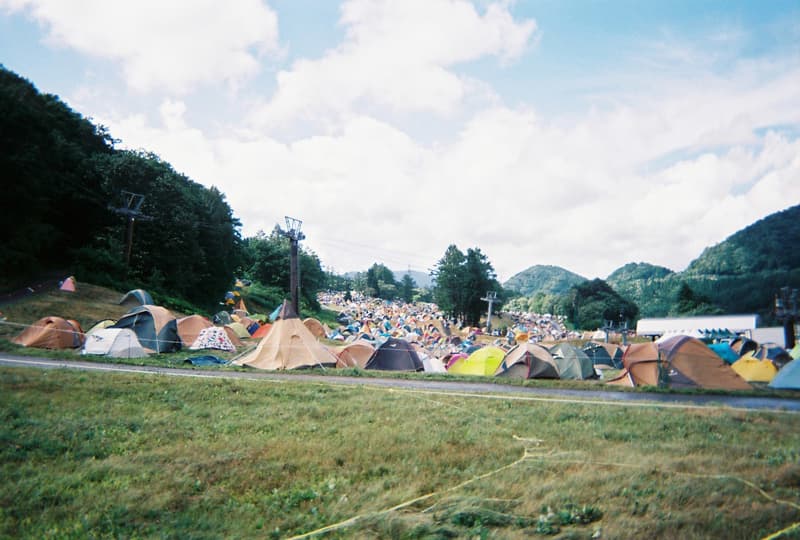 Back to Film：HYPEBEAST 編集部の等身大 FUJI ROCK FESTIVAL '18 備忘録  ファッション業界の方々から学生時代の部活の先輩まで、『HYPEBEAST』のリアルな日常を使い捨てカメラで記録した「FUJI ROCK」の番外編企画 山の天気は変わりやすい。「FUJI ROCK FESTIVAL '18」の会場となった苗場スキー場は途中に台風の通過もあってか、激しい雨と燦々と降り注ぐ日照りの繰り返しで、どこかの先人が作った言葉の意味を再認識した3日間だった。『HYPEBEAST』では連日、臨場感溢れるアーティストのステージパフォーマンスを中心とした速報や、タフな環境下でもファッション＞機能性のマインドを持ち合わせる人々を撮影したストリートスナップをご紹介してきた。これらの記事制作の背景に少しだけ触れると、取材は日中から場合によっては深夜にまで及び、翌日朝は写真の編集と記事の執筆、現場では聴きたいアーティストのライブを余裕綽々で堪能できる時間はほとんどなく、山道の移動と悪天候がプレゼントしてくれる疲労の蓄積で、夜はホテルに戻るや否や汗を流し、次の日に備えて寝る、これがリアルである。  しかし、移動の最中や束の間の休憩中に遭遇する、日頃からお世話になっているファッション/音楽業界の方々、夜遊び仲間、中学時代の部活の先輩、久しぶりに会った音好きの友人たちと言い合うライブの感想、たわいもない会話、そしてビールでの乾杯は、編集部にとっては紛れもない「FUJI ROCK」の醍醐味なのだ。  そこで、我々は本気の仕事の裏側で、ポケットに使い捨てカメラを忍ばせ、柵前の景色から美味しいご飯を提供してくれたお食事処の皆さんまで、実際にいたロケーションと遭遇した仕事仲間＆友人を気の向くままにパシャパシャと撮影。このカジュアルな企画では、上原のセレクトショップ『UFO（UPPER FIELD ONE）』の千寿公久、過去に#Essentialsに登場してくれた『Mastered』編集長の三木系大、水原佑果や武居詩織＆きなりのモデル勢など、レポート記事とストリートスナップには登場していない人の姿も収めることができた。暗かったり、写真の構図が雑だったり、ピントが合っていないのはご愛嬌。是非、『HYPEBEAST』編集部2名が緩めに切り取った「FUJI ROCK FESTIVAL '18」の等身大備忘録を上のフォトギャラリーから楽しんでみてほしい。  まだ「FUJI ROCK FESTIVAL '18」の初日、二日目、最終日のレポートとストリートスナップをチェックしていない方は、そちらもお見逃しなく。