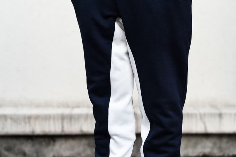 KIM JONES GU PRODUCTION ラストコレクションの一部アイテムを先行紹介 8月31日(金)の全商品ラインナップ発表に先駆け、『HYPEBEAST』編集部の元に到着した注目アイテムを緊急撮影 〈GU(ジーユー)〉がKim Jones(キム・ジョーンズ)とのコラボコレクション“KIM JONES GU PRODUCTION”のラストコレクションを発表してから間も無く、『HYPEBEAST』編集部の元に〈GU〉陣営から本コレクションの一部アイテムが到着した。 ティーザー画像にも登場するナバホブルゾンはポリエステル/レーヨン/ポリウレタンのボディで、ロゴ入りのダブルジップを採用し、後ろ身頃の裾はリブ状に。裏地も張られ、ブルゾンそのものに重量感があるため、冬場には高い防寒性を発揮してくれるだろう。また、チェック柄のマフラーはアクリル製のためにウールのようなチクチクとした肌触りを感じることがなく、表面には“KIM JONES”のロゴが配されている。また、左胸元に愛犬の刺繍パッチを施したスウェットフルジップパーカは、背中にも愛犬のモチーフをプリントすると同時に、その下には〈Dior(ディオール)〉のメンズデザイナーの名前をボディと同色の糸で立体的に刺繍。その他にはスエット生地のトラックジャケット&トラックパンツはネイビーにホワイトの切り替えが秀逸で、バックパックにはショルダーストラップに“KIM JONES”のロゴ入りテープをあしらい、フロントポケットに“AMERICA”のロゴがセットされている。 “KIM JONES GU PRODUCTION”のラストコレクションは9月14日(金)より発売開始となるが、全商品ラインナップは2018年8月31日(金)に特設ページにて公開されるとのこと。本コレクションのコンセプトについては、こちらからご確認を。