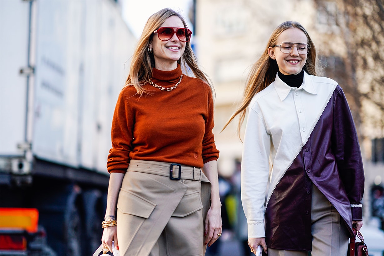 Pernille Teisbaek (L) wears an orange top with a golden necklace, a beige skirt, a white Chloe bag, burgundy leather boots ; a guest (R) wears glasses, a white and purple leather jacket, flare pants,outside Chloe
