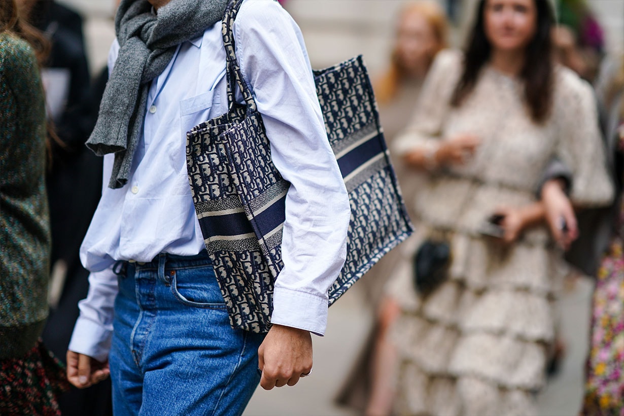 A guest wears a shirt, a gray wool pullover, blue jeans, a Dior monogram tote bag, during London Fashion Week September 2019 on September 16, 2019 in London, England