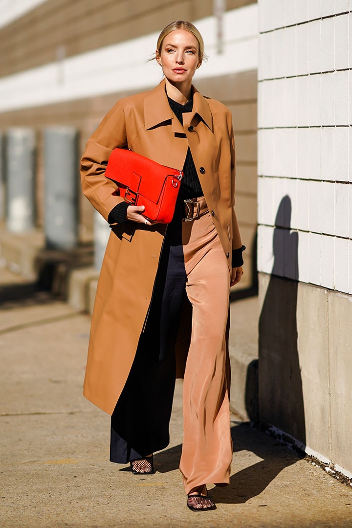 Leonie Hanne wears a red Fendi bag, a brown long coat, flared pants, outside Self Portrait, during New York Fashion Week Fall-Winter 2020, on February 08, 2020 in New York City